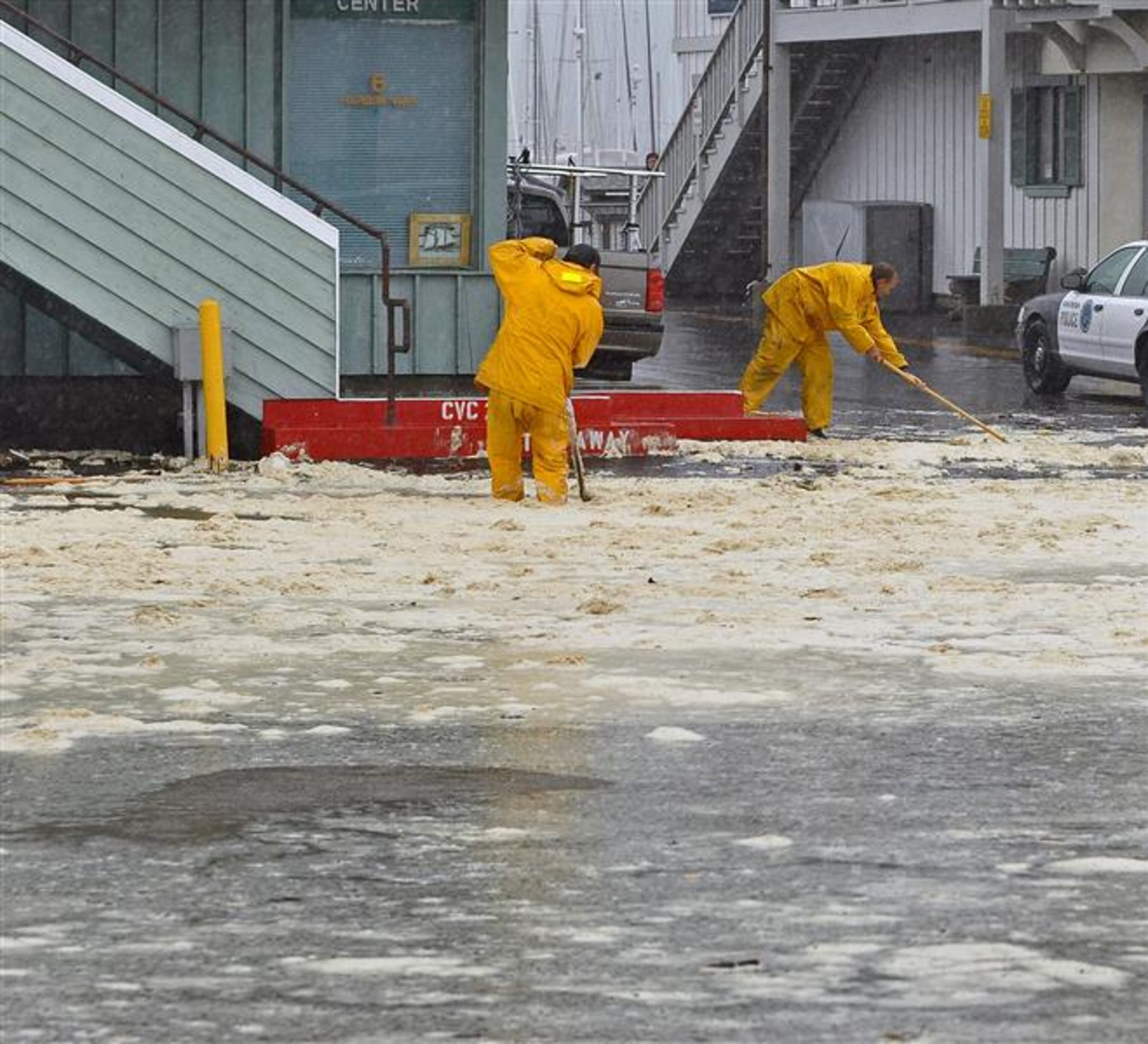 Workers try to clear drains at the Santa Barbara, Calif., harbor after high waves breached a sand berm and flooded the parking lot Saturday, March 1, 2014. The storm marked a sharp departure from many months of drought that has grown to crisis proportions for the state’s vast farming industry. However, such storms would have to become common to make serious inroads against the drought, weather forecasters have said. (AP Photo/Santa Barbara News-Press, Mike Eliason)