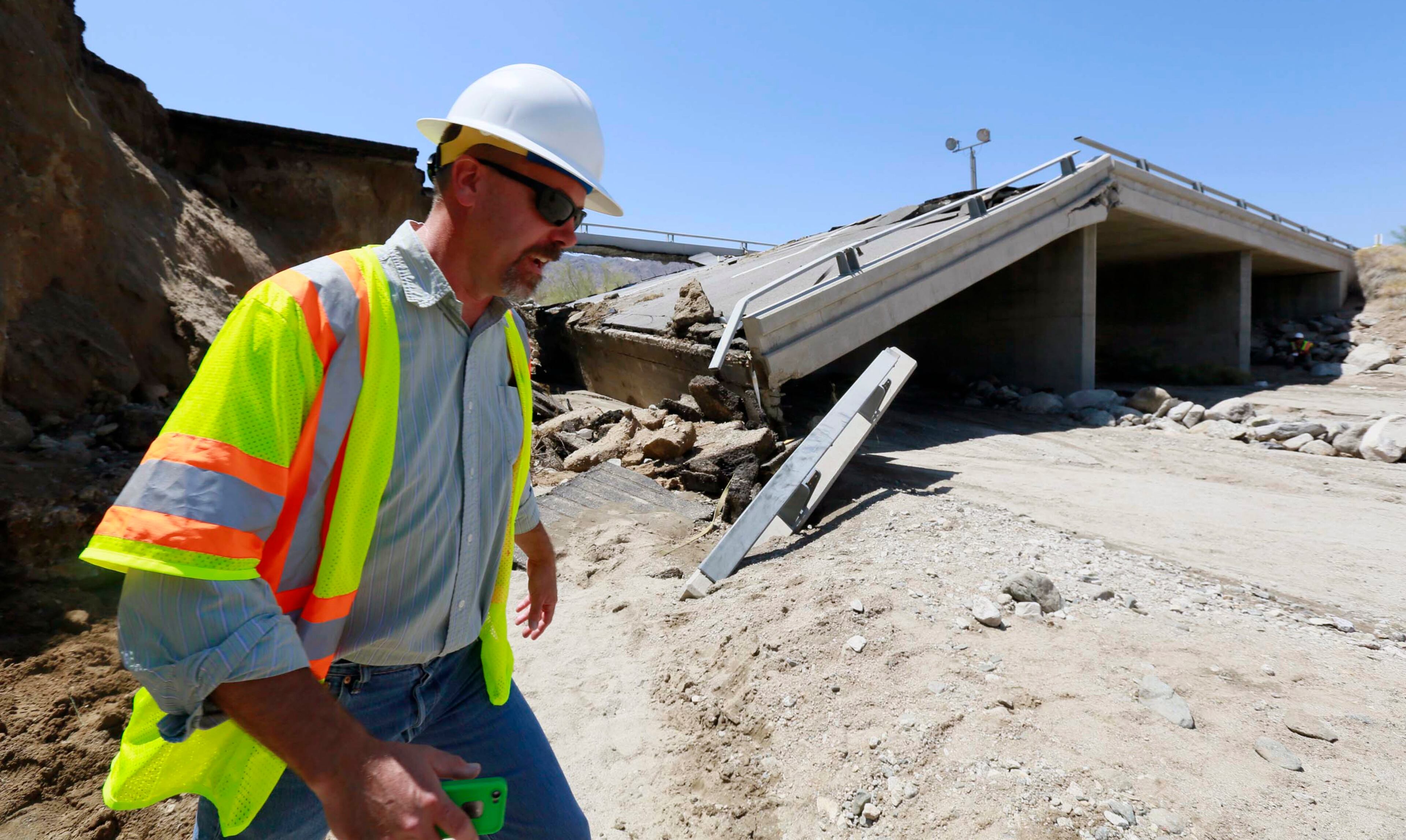 Mike Ristic, senior Transportation Engineer for California Department of Transportation, inspects a collapsed bridge that was washed out along Interstate 10 in Southern California, Monday, July 20, 2015. All traffic along one of the major highways connecting California and Arizona was blocked indefinitely when the bridge over a desert wash collapsed during a major storm, and the roadway in the opposite direction sustained severe damage. (AP Photo/Nick Ut)