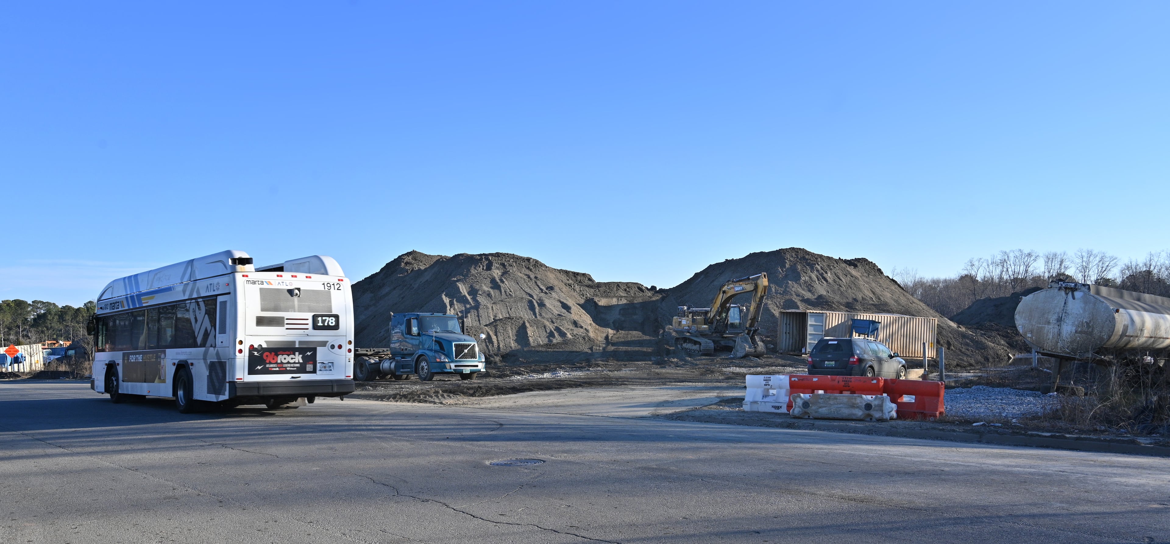 A MARTA bus passes waste piles on a site run by TAV Holdings Inc. on Wednesday, January 26, 2022. The EPA is continuing to probe off site contamination from the site, and a separate investigation by OSHA into workplace conditions at the facility is underway.