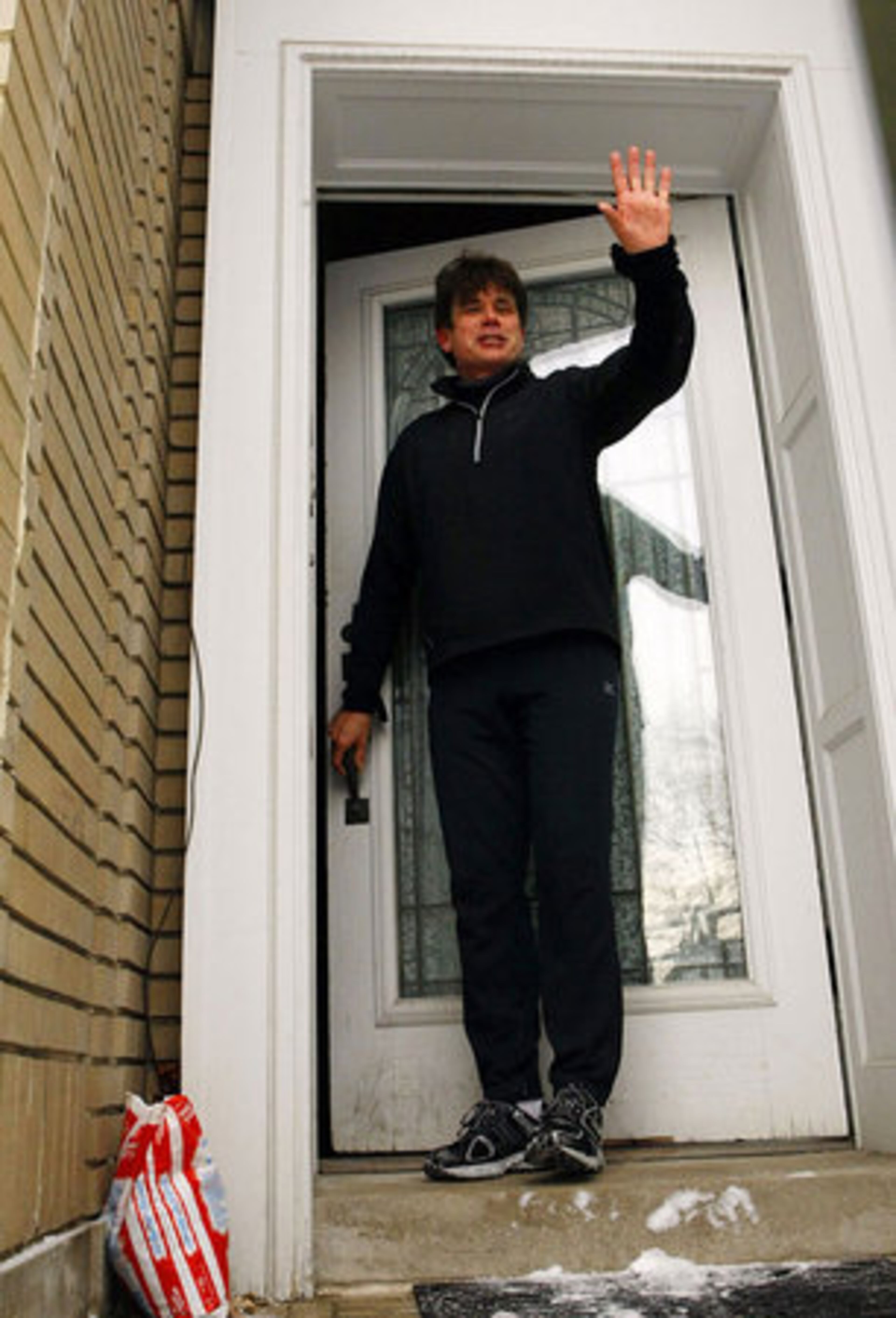 Blagojevich waves to reporters as he returns home from a morning run - hours before the house voted to impeach him.