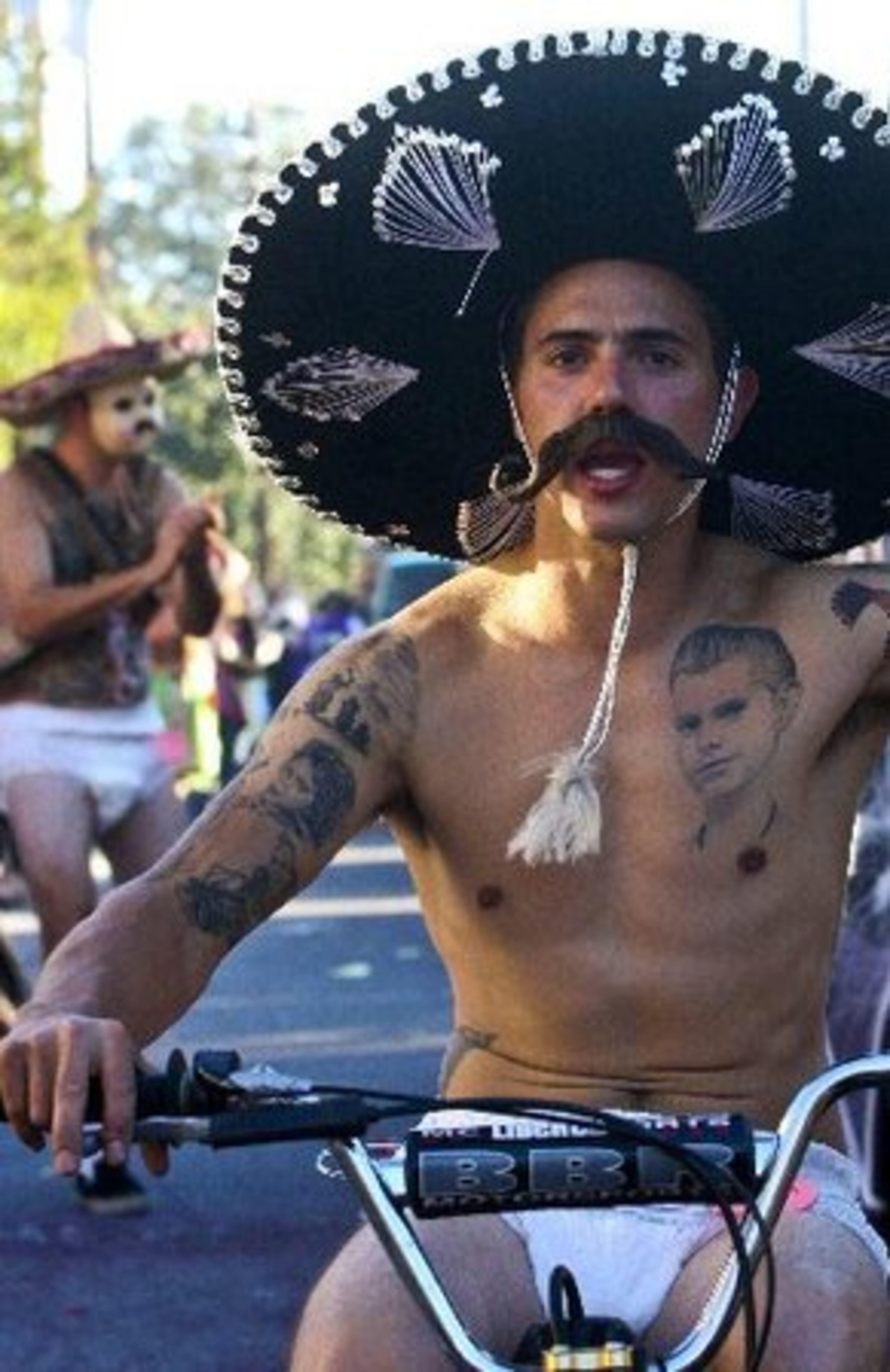 A man wearing a sombrero, tattoos and not much else rides in the 10th Annual Little Five Points Halloween Parade.