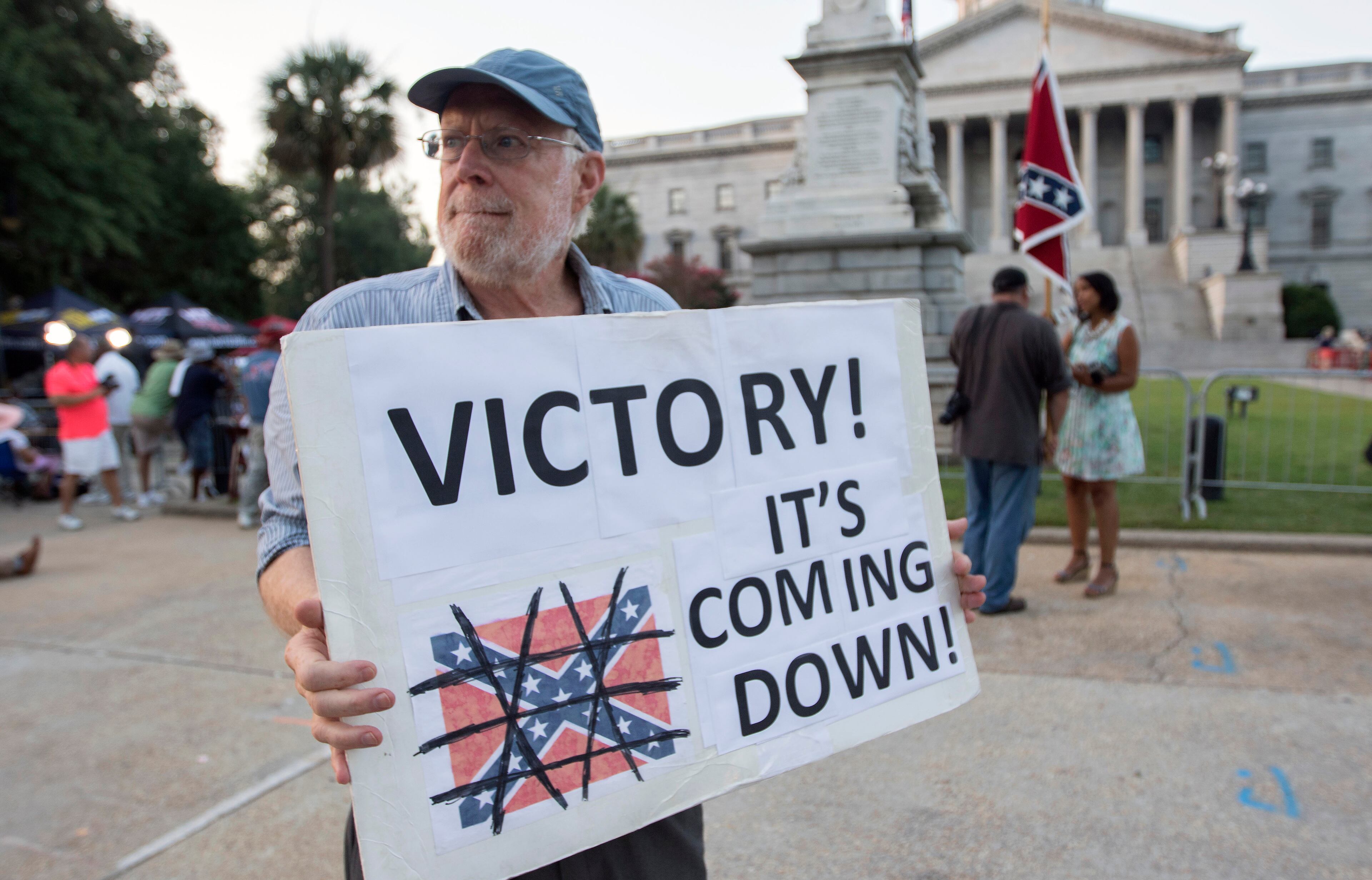 Tom Clements holds up a sign as he waits for the Confederate battle flag to be removed from the grounds of the State House in Columbia, S.C., the morning of July 10, 2015. In a historic moment for South Carolina, the flag is set to be removed from its 30-foot pole on Friday morning. (Stephen B. Morton/The New York Times)