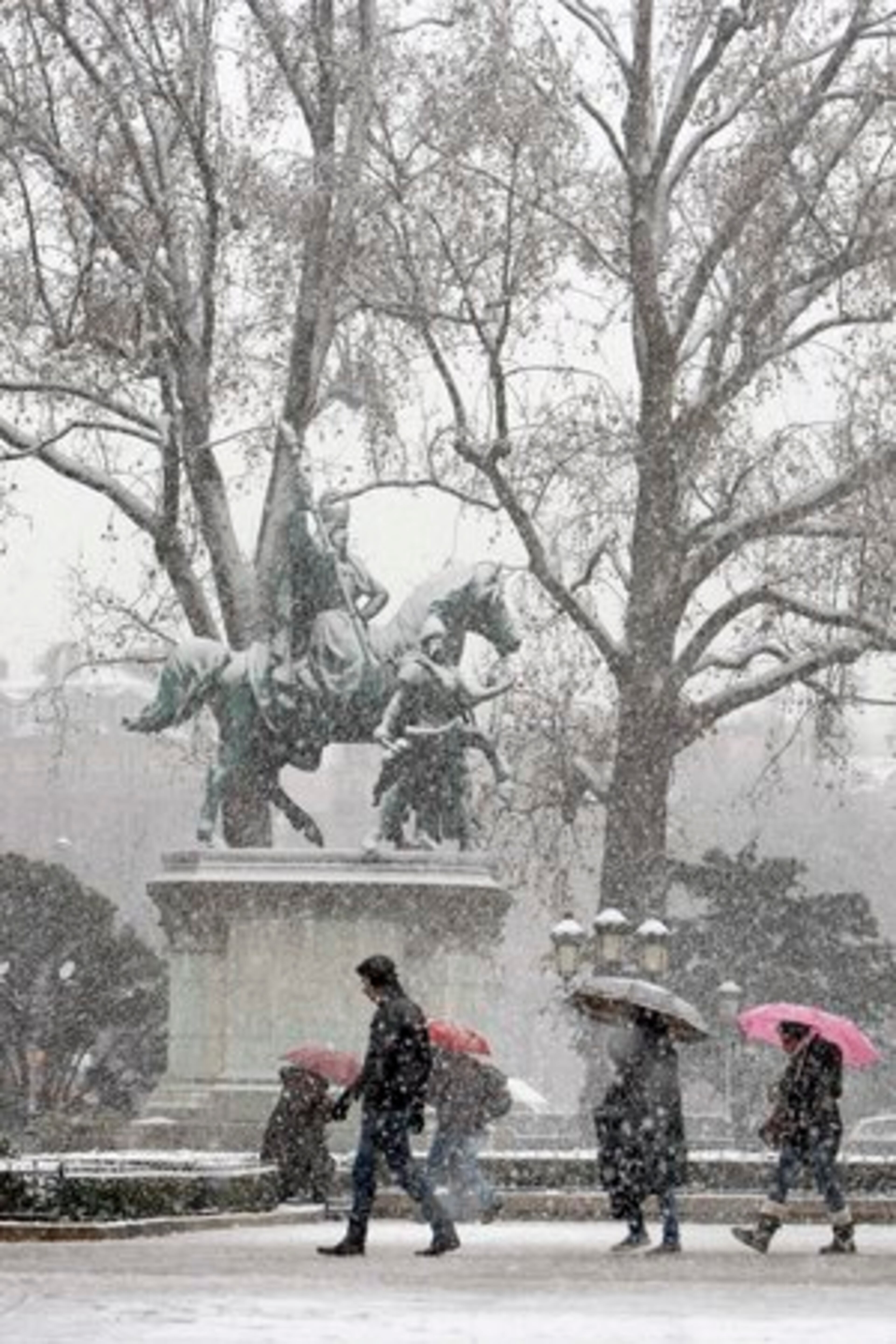 Tourists are seen near Notre Dame cathedral in Paris, Wednesday Dec. 8, 2010, as a snow storm disturbs the traffic in the French capital.