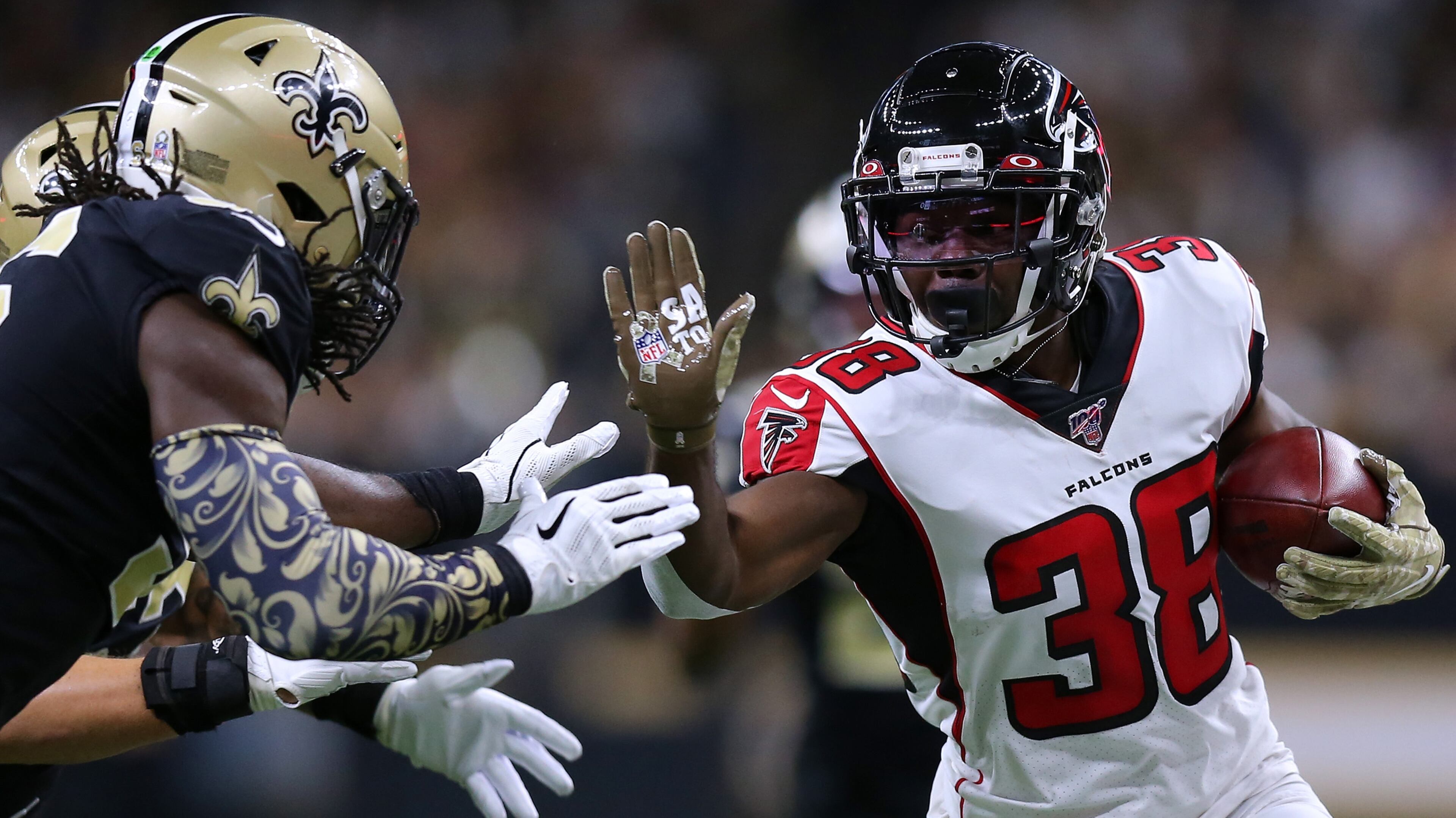 Falcons running back Kenjon Barner runs with the ball as the Saints' Demario Davis and A.J. Klein defend during the first half of a game Nov. 10, 2019, at the Mercedes Benz Superdome in New Orleans.