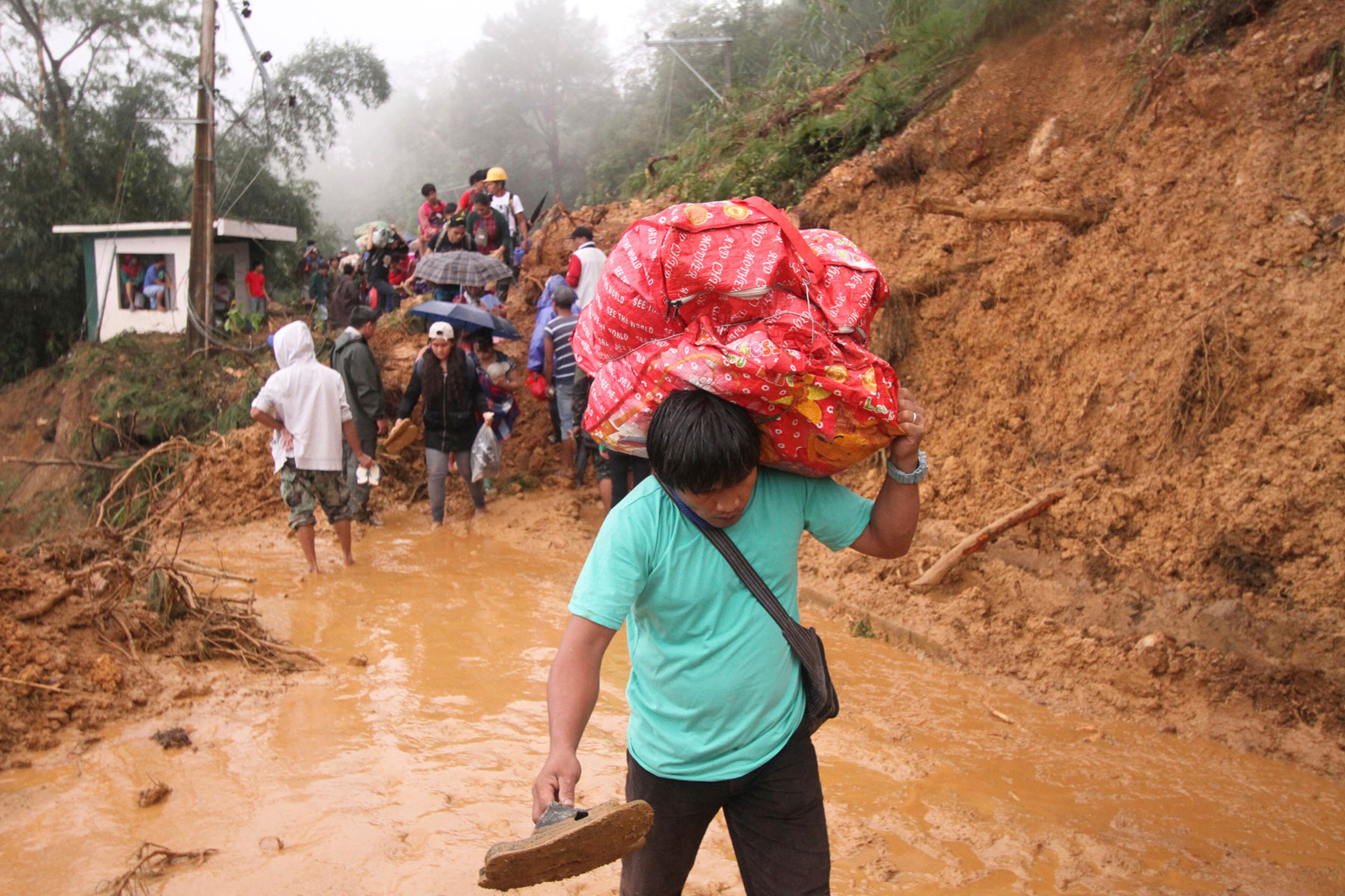 Families and relatives of miners in Itogon township, Benguet province in the northern Philippines, carry their belongings as they evacuate following landslides which were triggered by Typhoon Mangkhut burying an unknown number of miners and isolating the township Sunday, Sept. 16, 2018. Typhoon Mangkhut barreled into southern China on Sunday after lashing the northern Philippines with strong winds and heavy rain that left more than dozens dead from landslides and drownings. (AP Photo/Jayjay Landingin)
