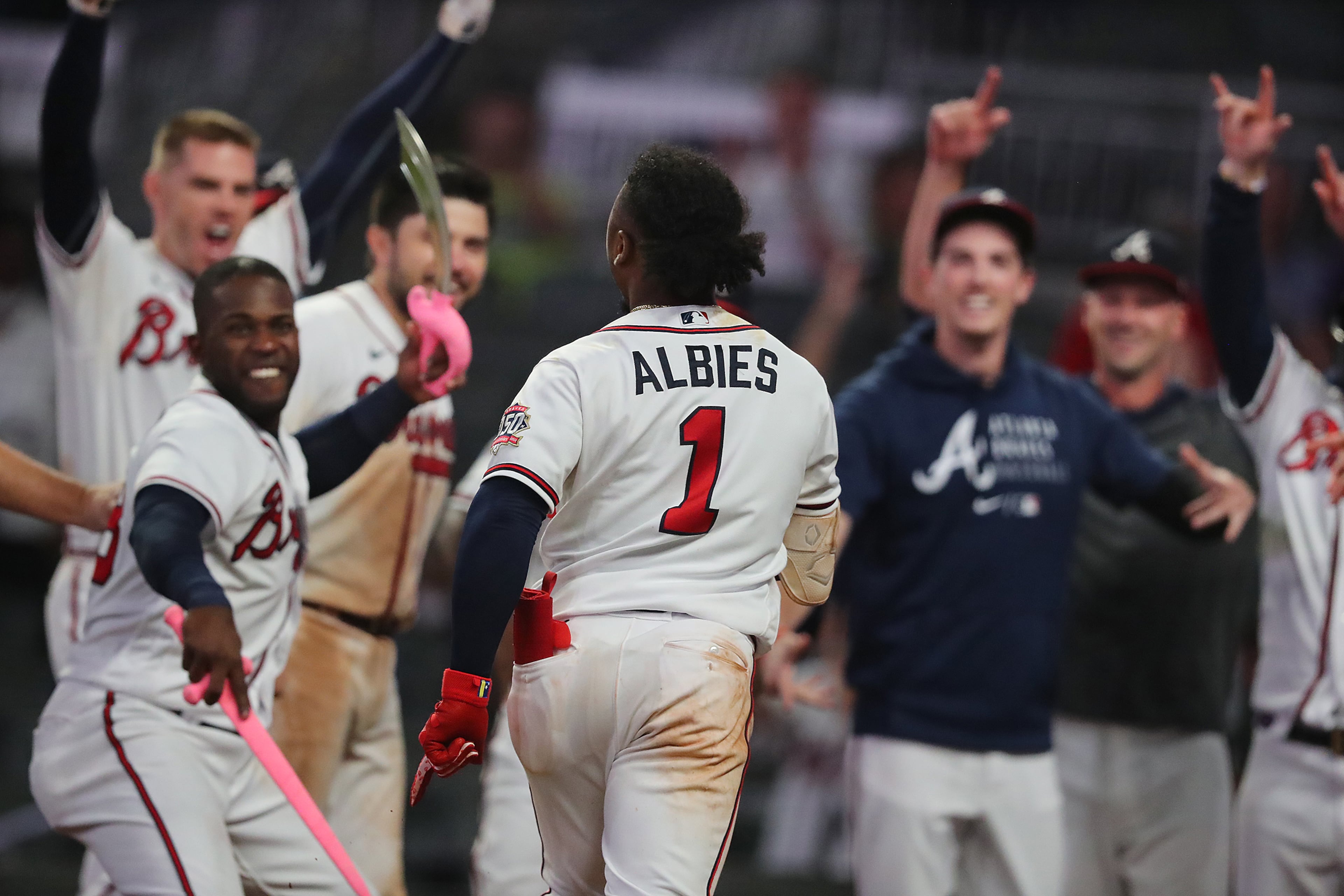 Braves players await second baseman Ozzie Albies at home plate after his homer. “Curtis Compton / Curtis.Compton@ajc.com”