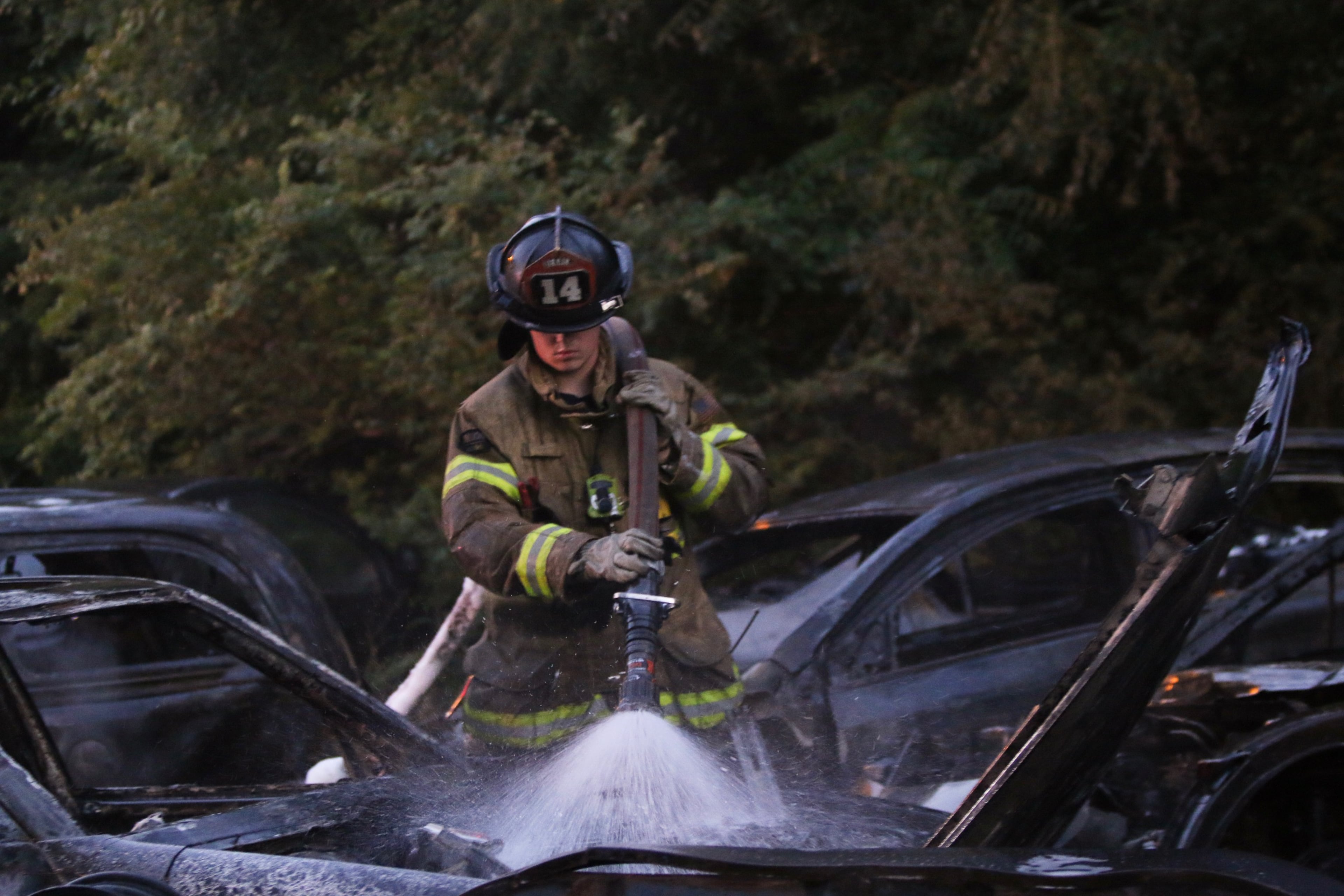 DeKalb County firefighter Joseph Brown works to put out a smoldering car parked at an auto body shop lot near Lithonia.