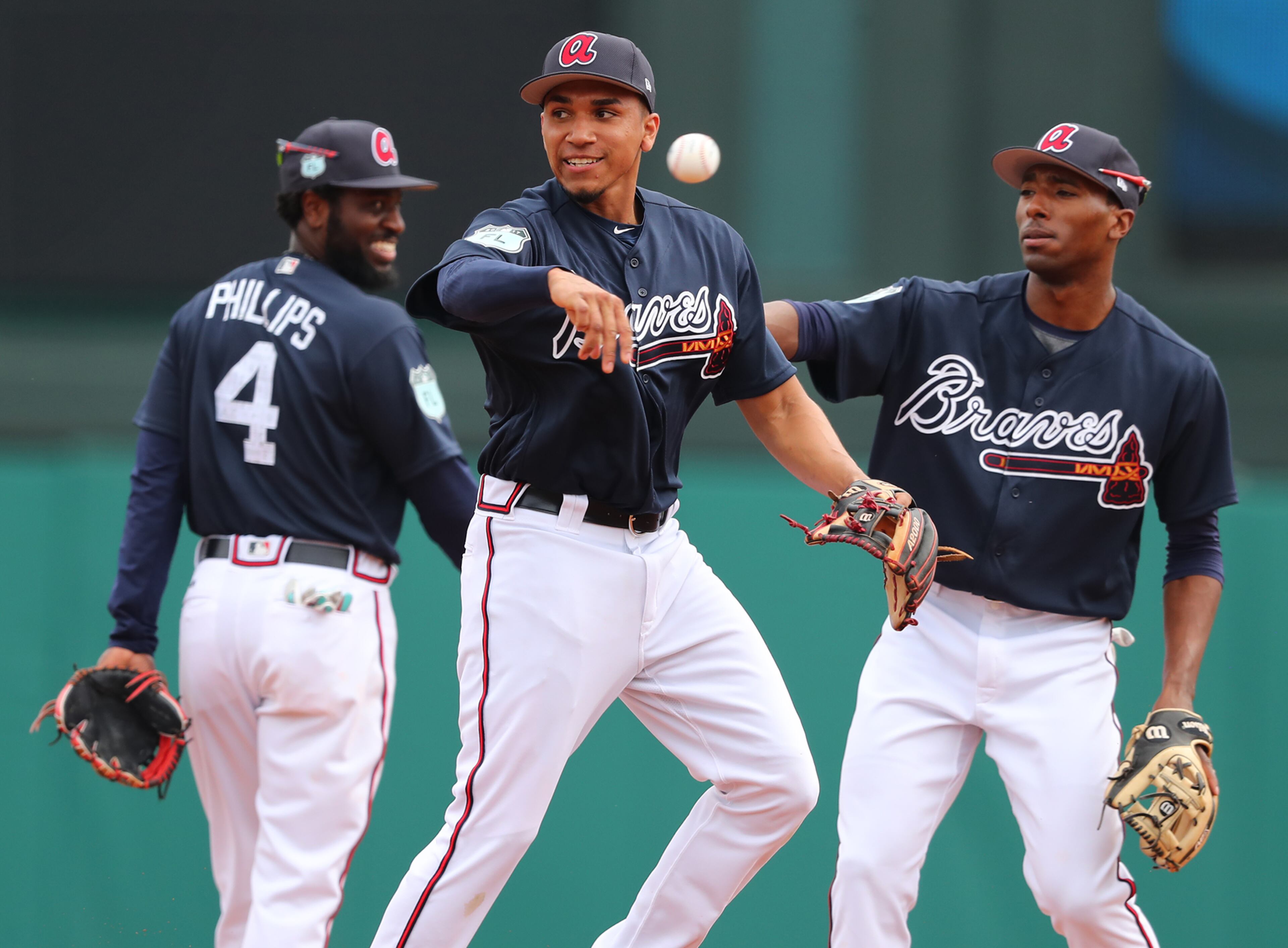 February 18, 2017, Lake Buena Vista, FL: Atlanta Braves infielder Johan Camargo fields a ground ball with Brandon Phillips and Travis Demeritte looking on during the first full squad workout at Champion Stadium on Saturday Feb. 18, 2017, at the ESPN Wide World of Sports in Lake Buena Vista. Curtis Compton/ccompton@ajc.com