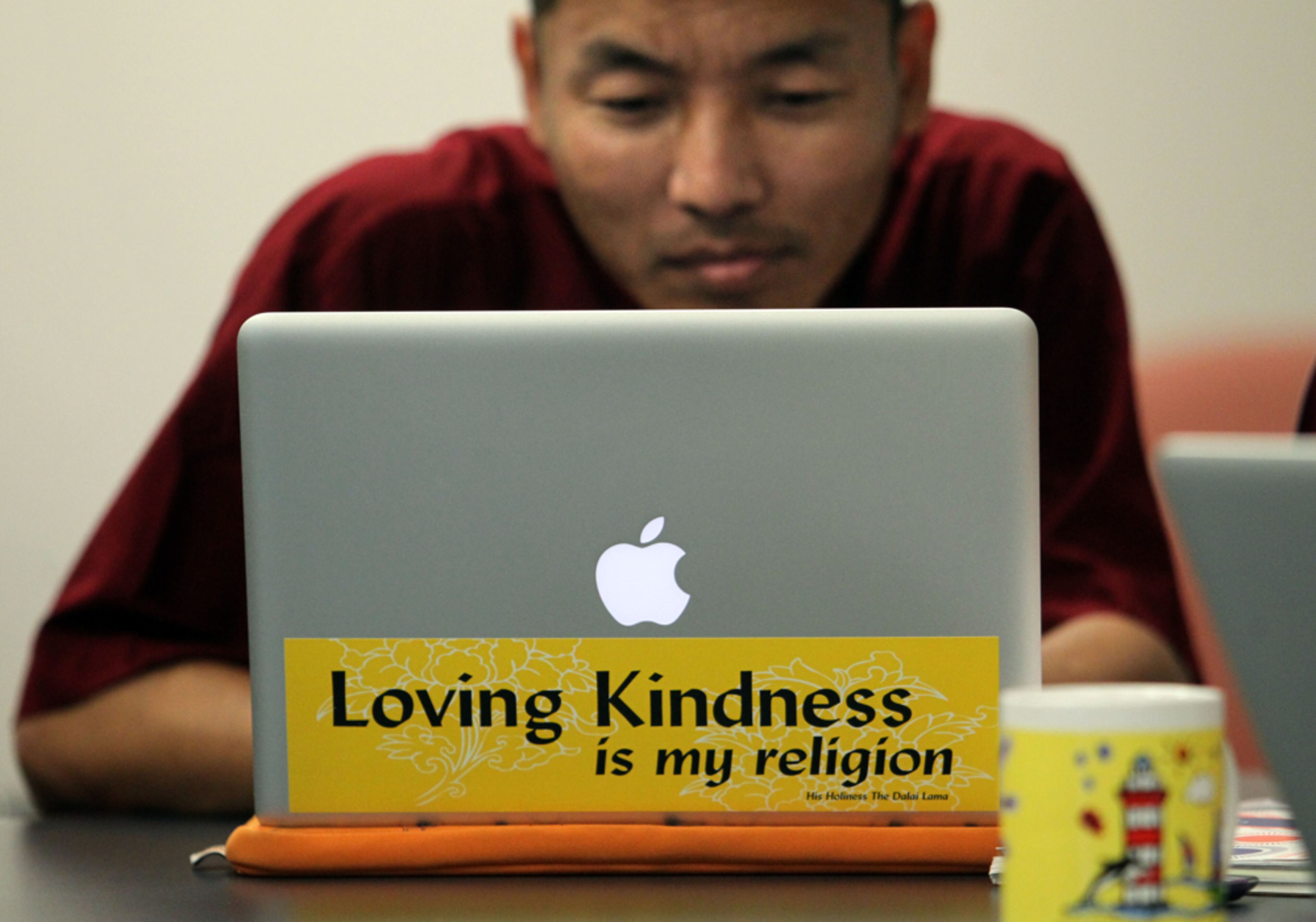 April 24, 2013 - Atlanta, Ga: With a bumper sticker quote by the Dalai Lama, "Loving kindness is my religion," on his laptop computer, Tibetan monk Ngawang Norbu works with other monks as they write new science books for Tibetan monks and nuns at Emory University Wednesday afternoon in Atlanta, Ga., April 24, 2013. Getz said, "This was a project that I did on six Tibetan monks that were finishing up their 3-year study at Emory. This was one of the first images I took and still the most memorable from this project, just because it's a combination of two different cultures." JASON GETZ / JGETZ@AJC.COM