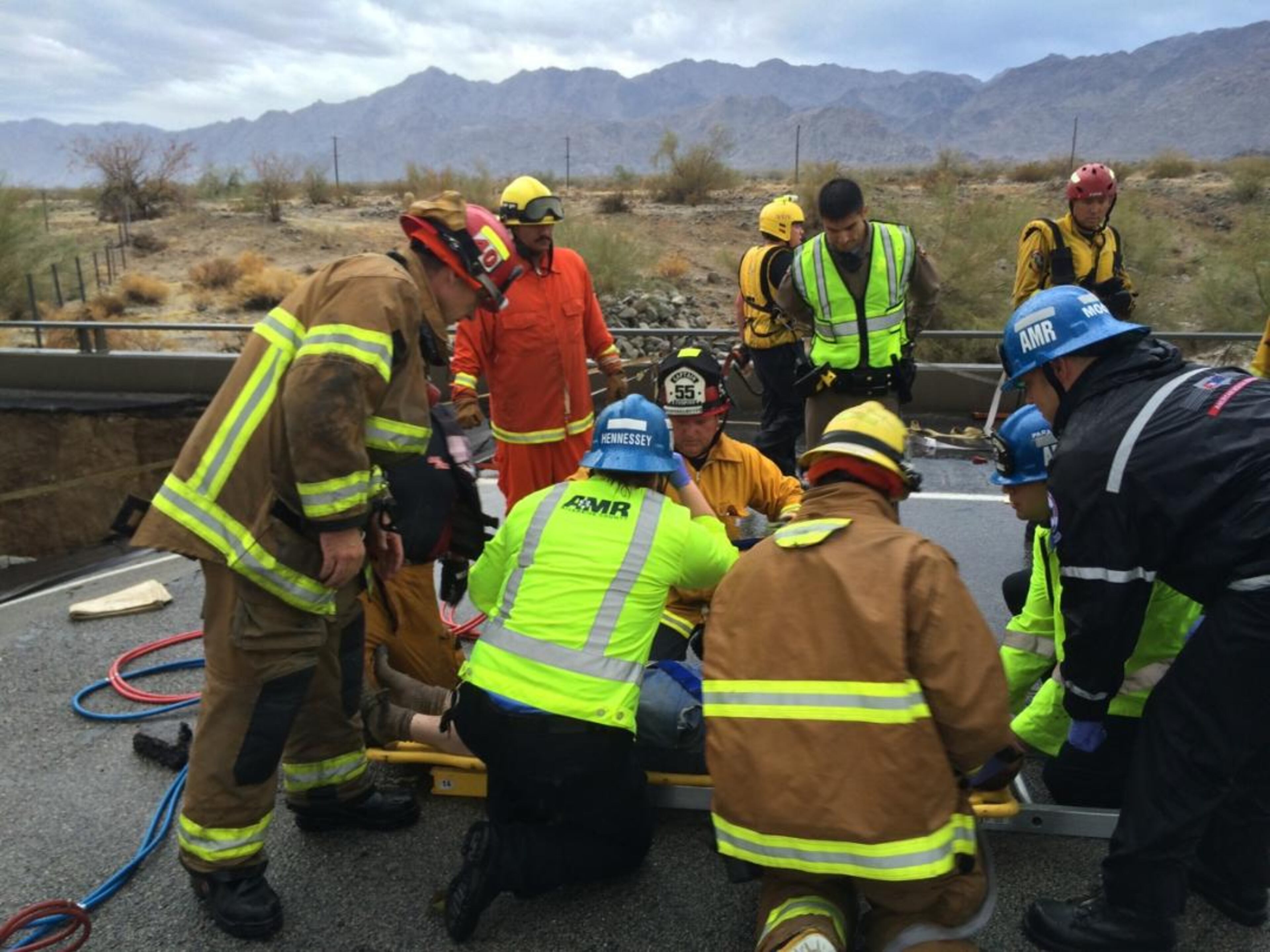 In this photo provided by the CAL FIRE/Riverside County Fire Department, emergency crews help a driver after their pickup truck crashed into the collapse of an elevated section of Interstate 10, Sunday, July 19, 2015, in Desert Center, Calif. The bridge, which carries the eastbound interstate about 15 feet above a normally dry wash, snapped and ended up in the flooding water below, the California Highway Patrol said, blocking all traffic headed toward Arizona. (Chief Geoff Pemberton/CAL FIRE/Riverside County Fire via AP)