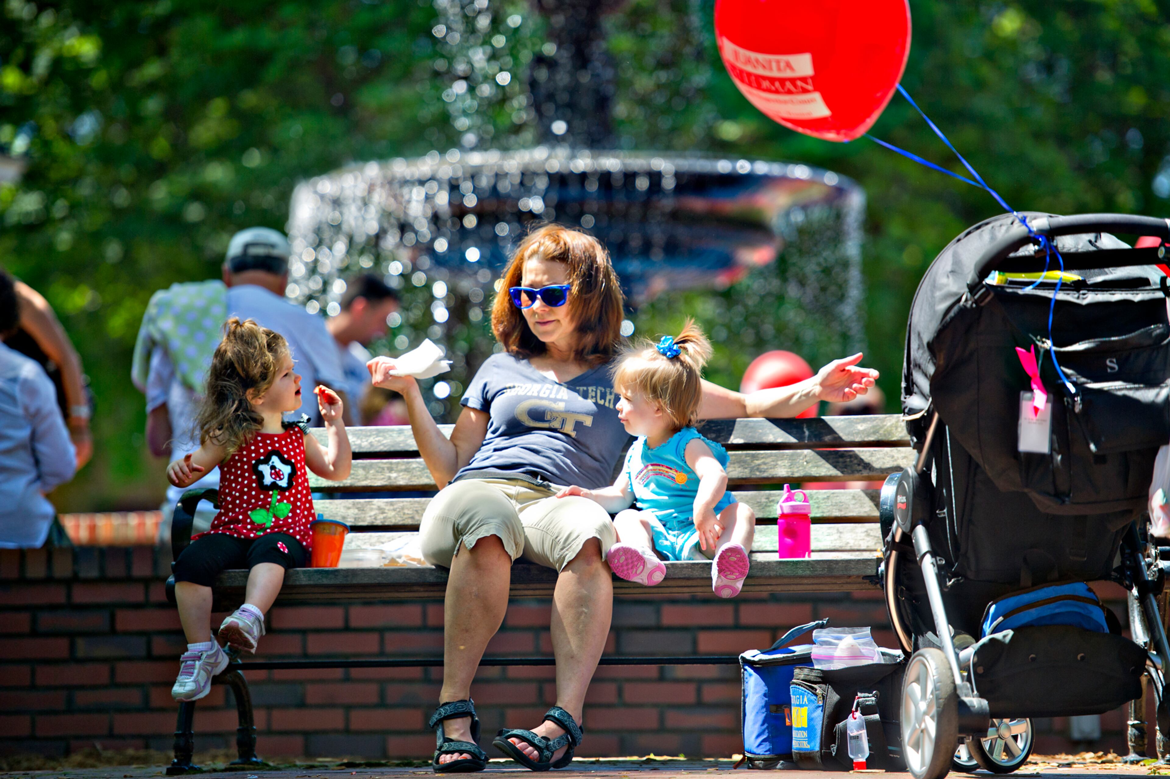 Tammy Shiflett (center) eats a snack with her granddaughter Lowery Collins (left) and niece Claire Shiflett as they sit on a bench during the May-retta Daze Arts & Craft Festival at Glover Park in Marietta on Sunday, May 4, 2014.
