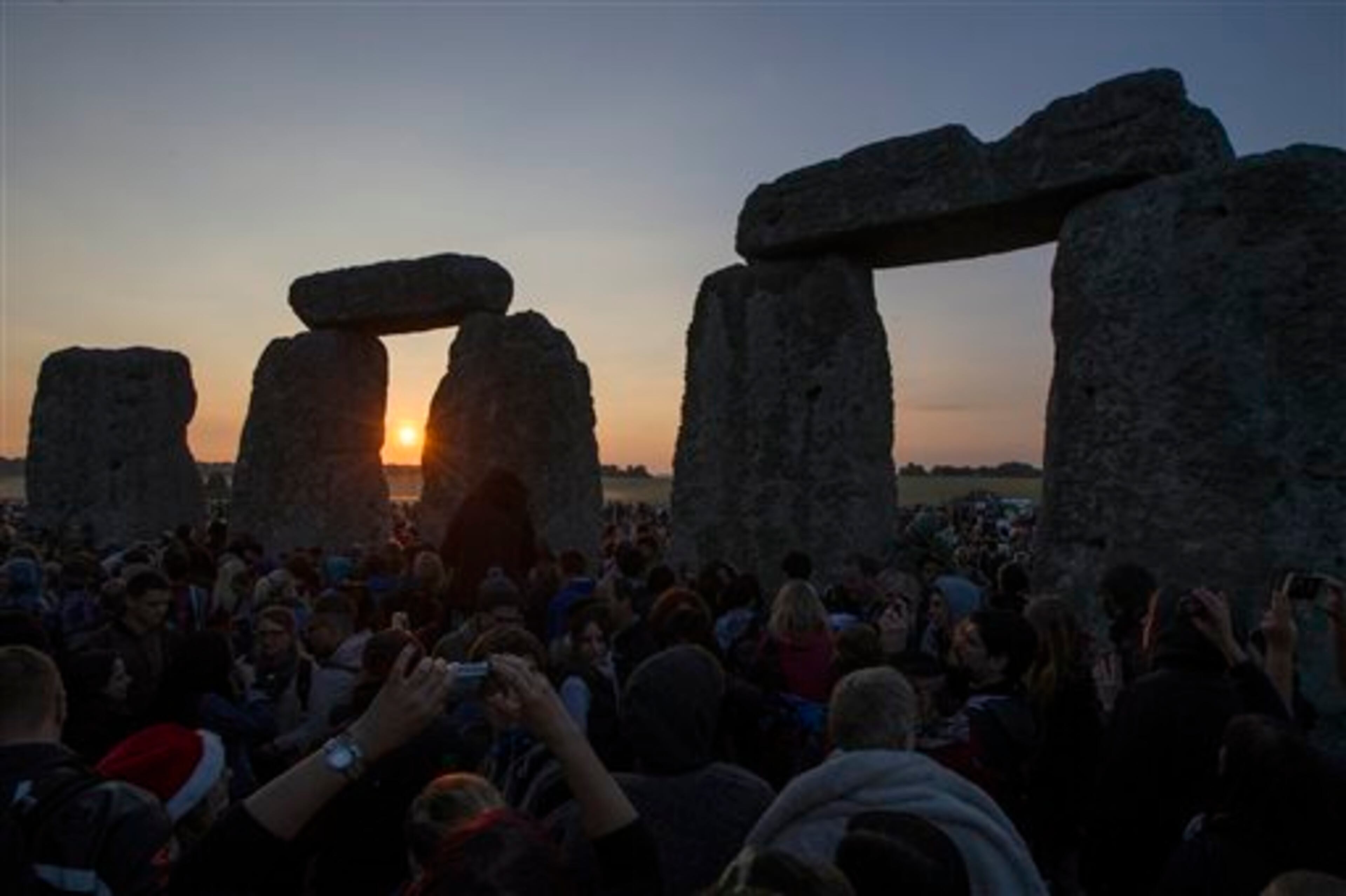 The sun rises as thousands of revelers gathered at the ancient stone circle Stonehenge, near Salisbury, England, to celebrate the summer solstice, the longest day of the year, Saturday, June 21, 2014. (AP Photo/Sang Tan)