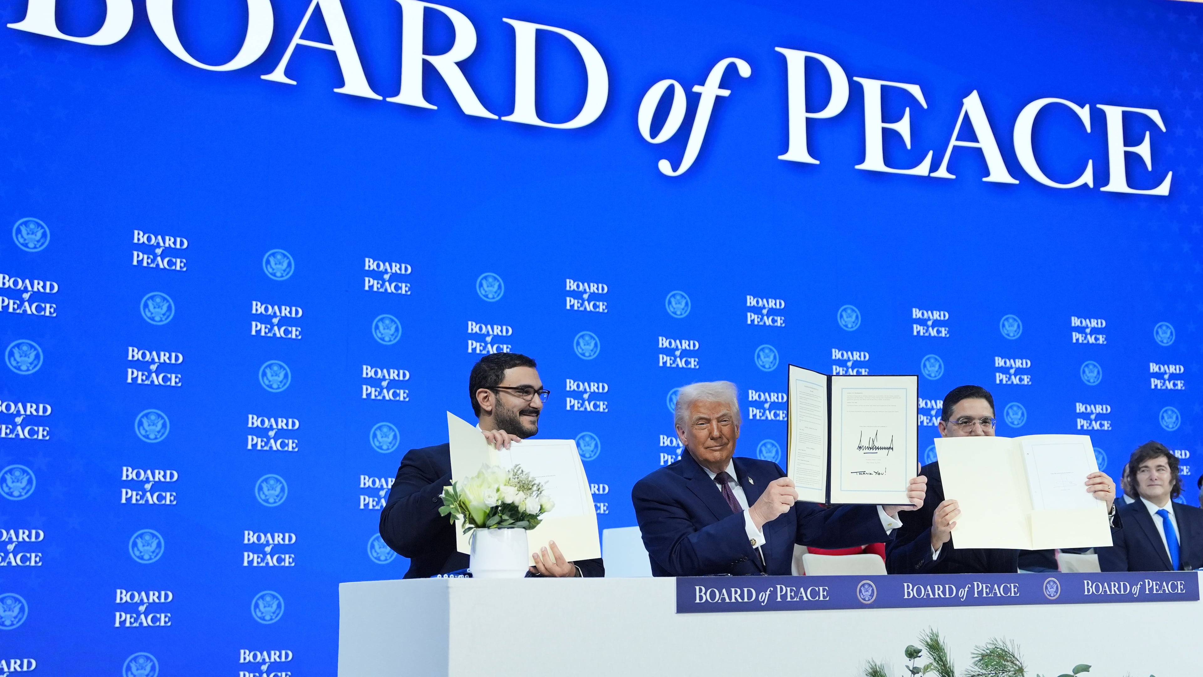 President Donald Trump, center, holds up a signed Board of Peace charter during the Annual Meeting of the World Economic Forum in Davos, Switzerland, Thursday, Jan. 22, 2026. (AP Photo/Evan Vucci)