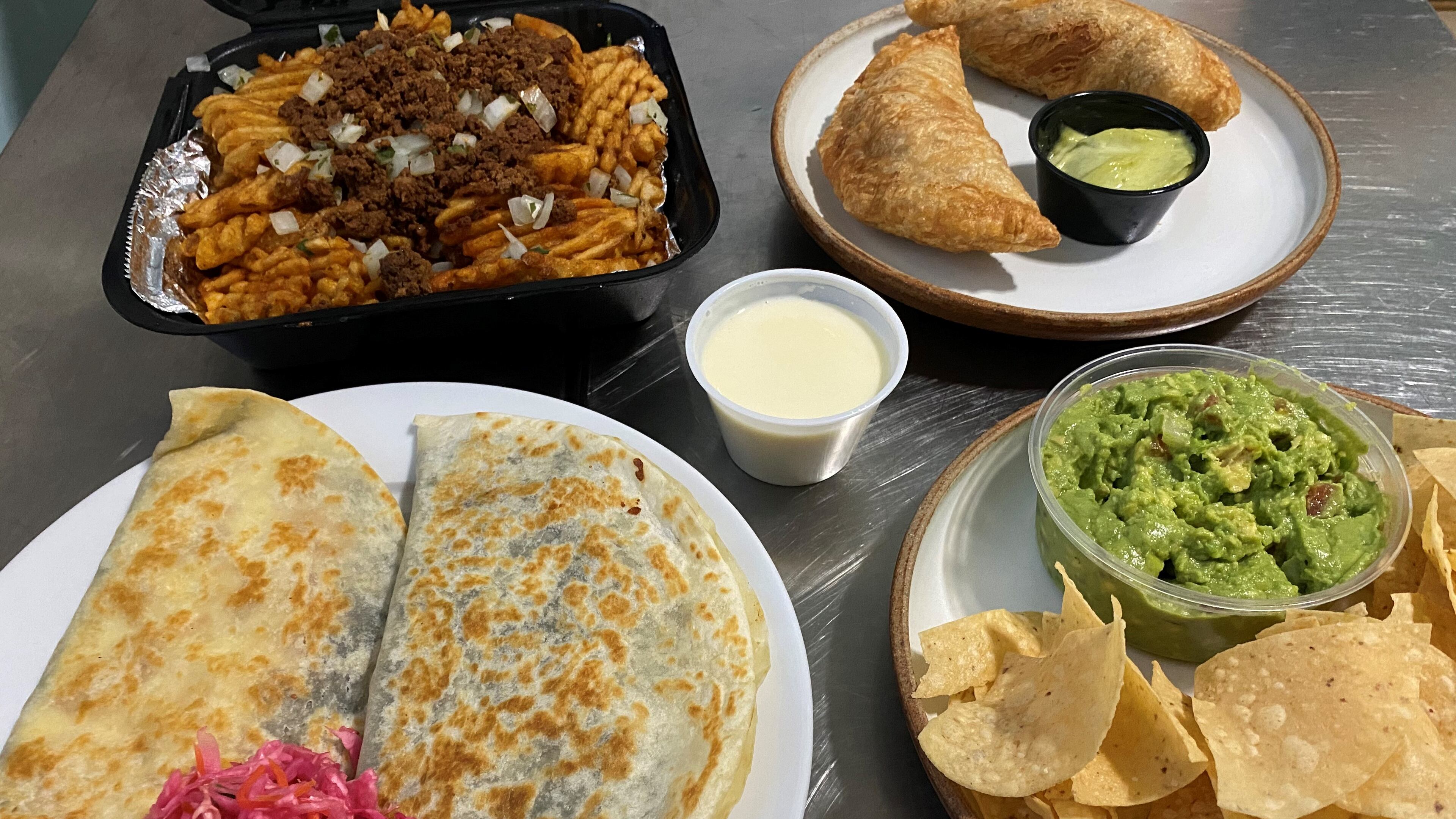 Takeout from Lean Draft House in southwest Atlanta: Top: chorizo fries and empanadas stuffed with carnitas. Bottom: a baleada (a Honduran specialty similar to a quesadilla; this one is stuffed with fried grouper); and guacamole and chips.
Wendell Brock for The Atlanta Journal-Constitution