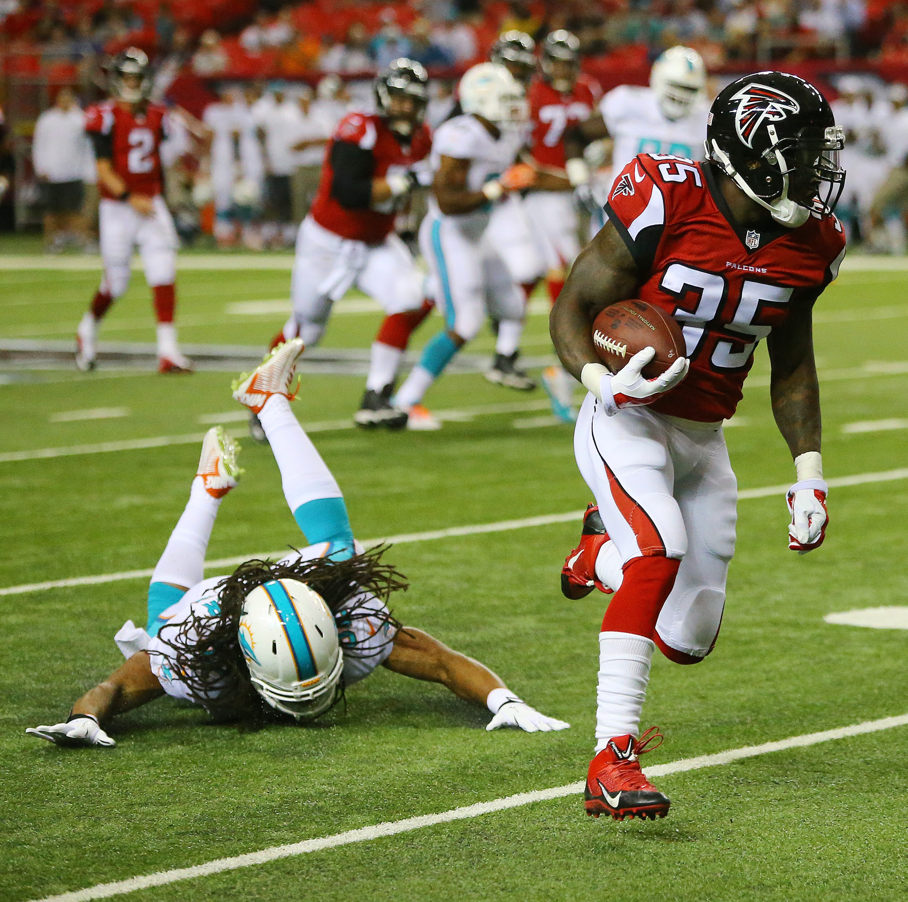 Falcons running back Antone Smith breaks away from Miami defenders for a long gain that was called back for a penalty during their NFL exhibition game on Friday, August 8, 2014, in Atlanta.