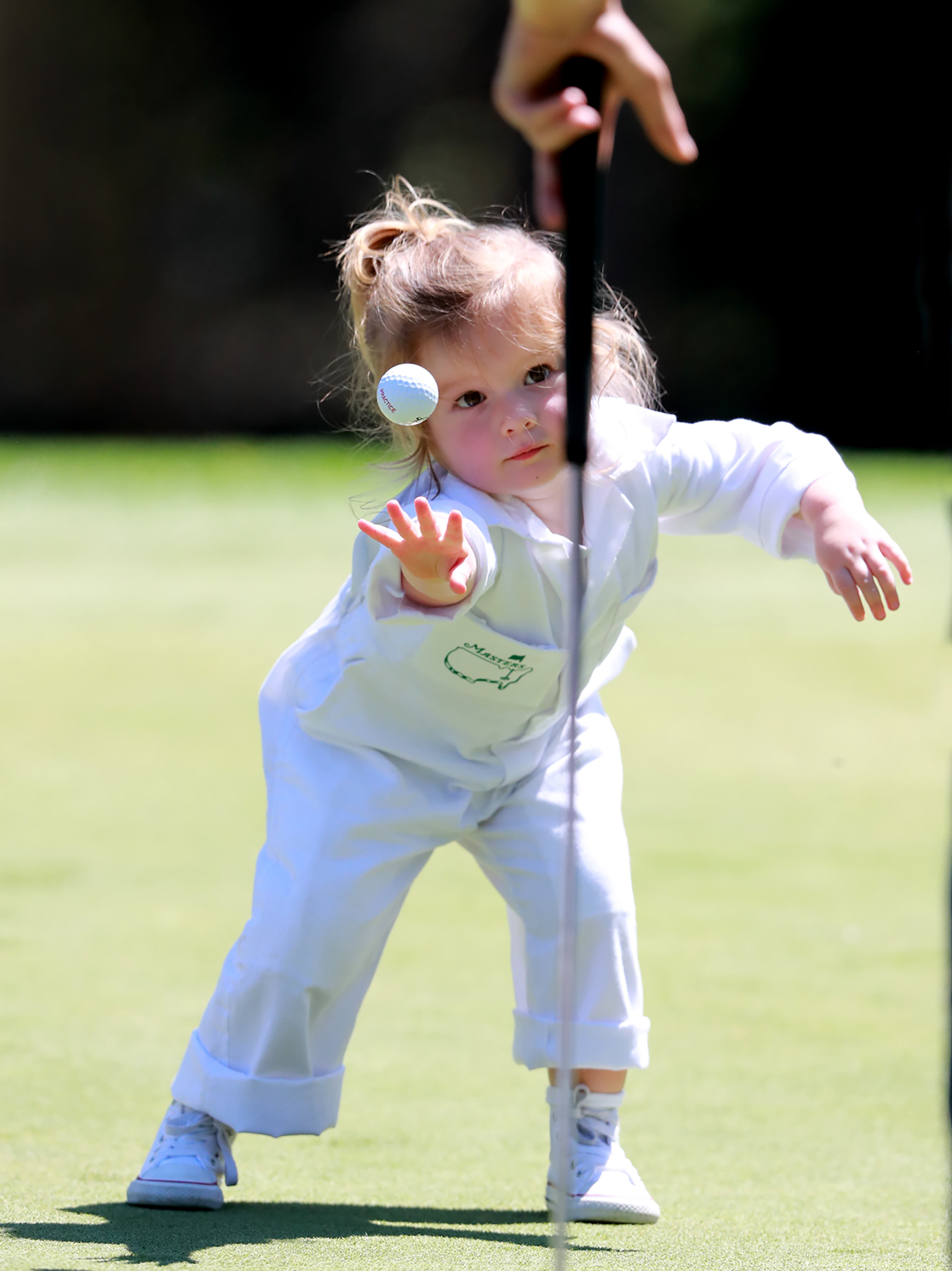 Shane Lowry's daughter Iris picks up his golf ball and gives it a toss before he can putt on the first hole. Curtis Compton/ccompton@ajc.com