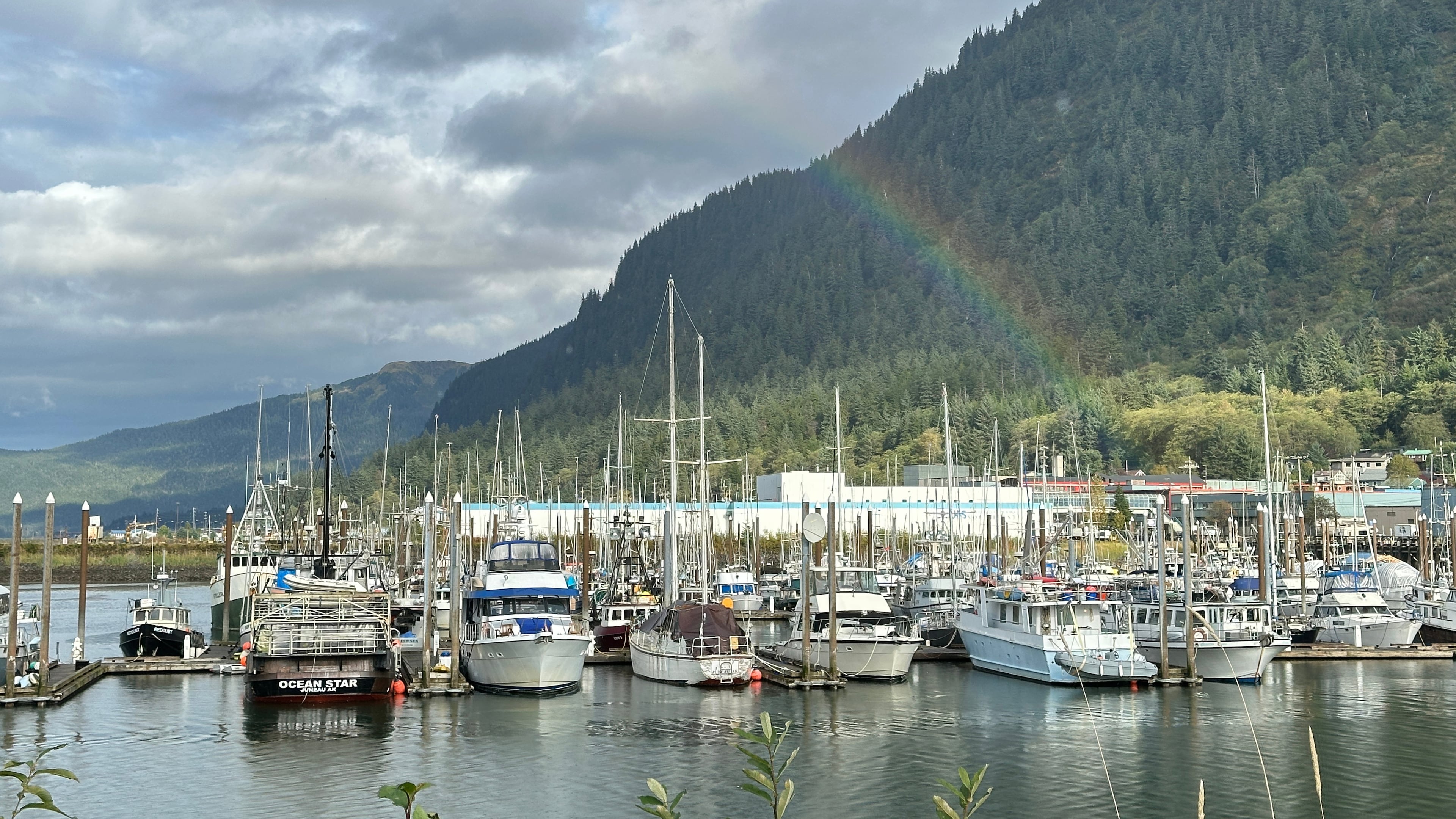This photo taken with a smartphone shows a partial rainbow arching over boats docked in a harbor in Juneau, Alaska, Thursday, Sept. 24, 2026. (AP Photo/Becky Bohrer)