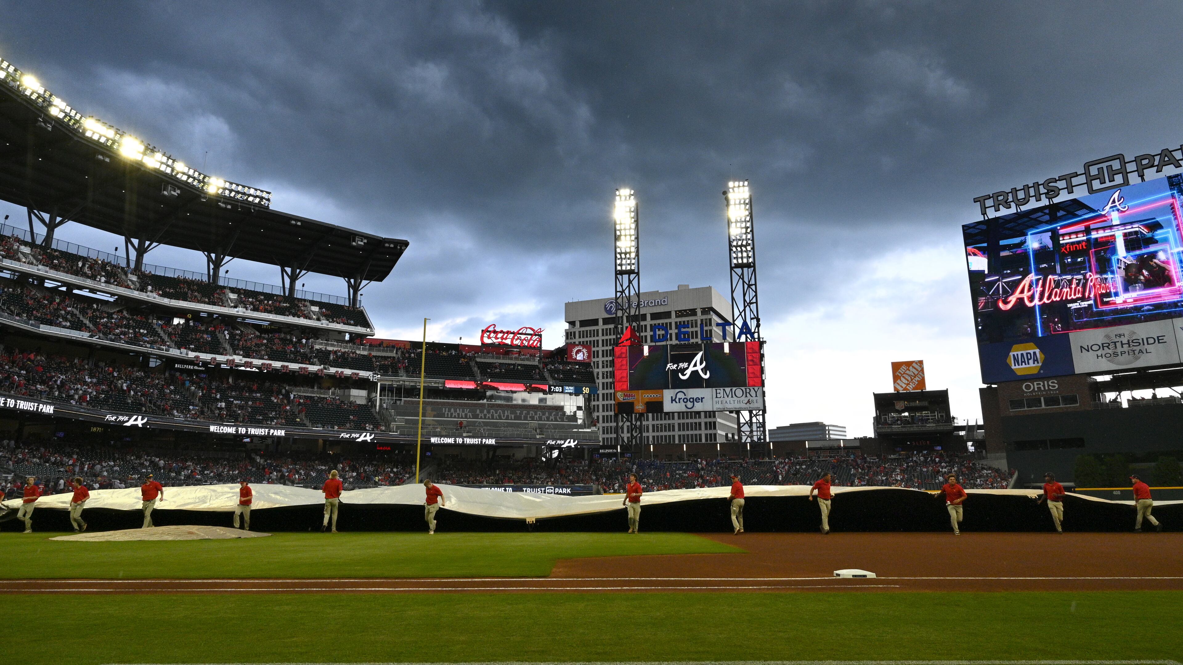 The grounds crew pulls out the tarp as dark clouds fill the sky before Atlanta Braves home game against Los Angeles Angels at Truist Park on Friday, July 22, 2022. (Hyosub Shin / Hyosub.Shin@ajc.com)