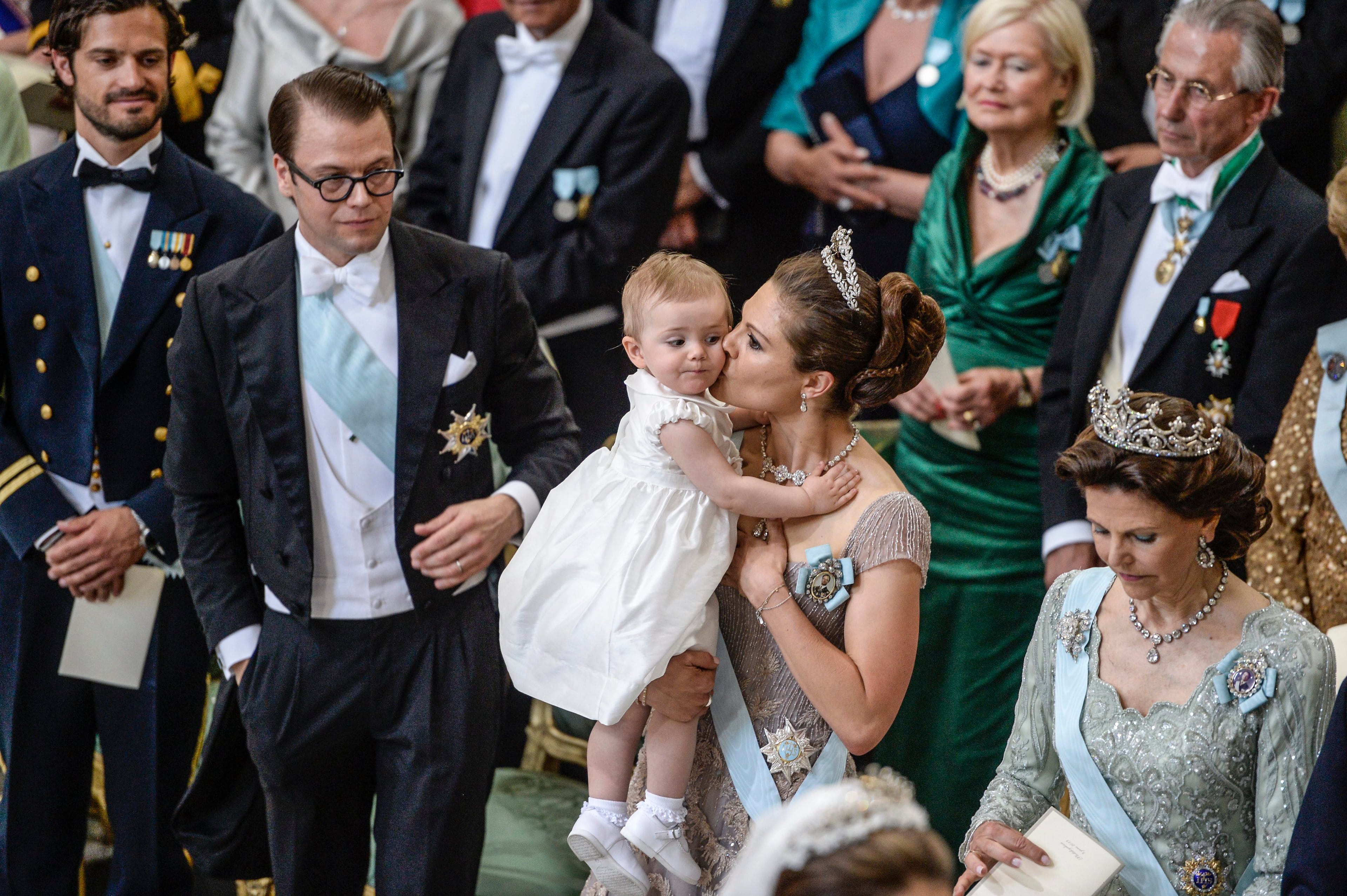 Sweden's Crown Princess Victoria kisses Princess Estelle as Prince Carl Philip, left, Prince Daniel, and Queen Silvia, right, look on during the wedding ceremony of Princess Madeleine and Christopher O'Neill at the Royal Chapel in Stockholm, Saturday June 8, 2013. (AP Photo/Jessica Gow)