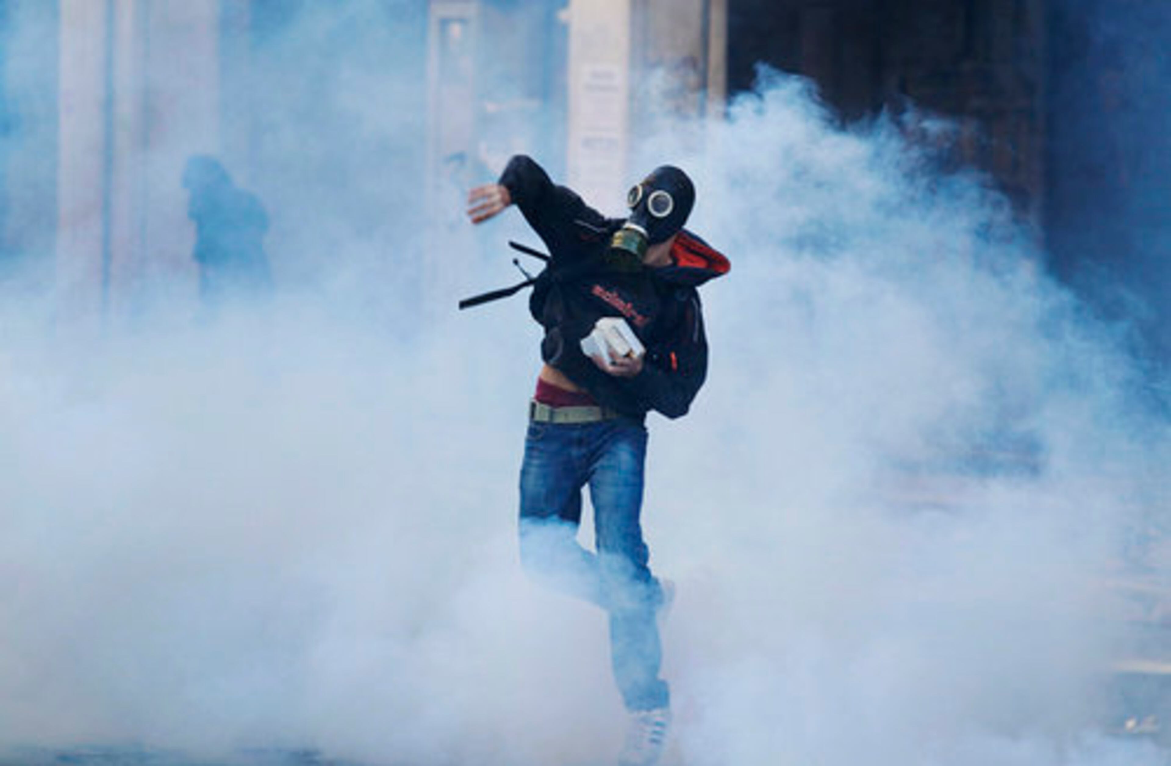 A protester throws a stone at riot police during clashes in Athens.