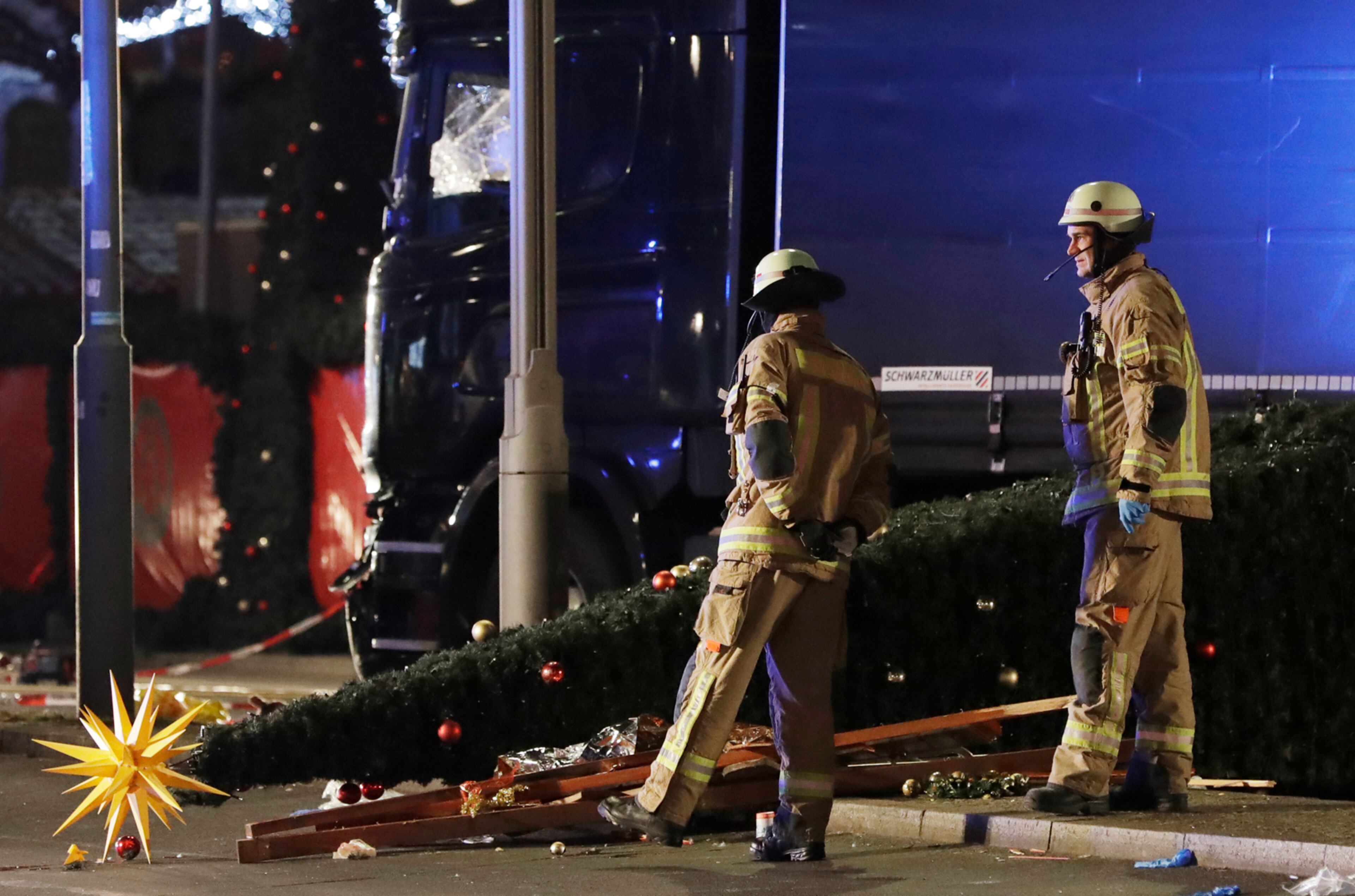Firefighters look at a toppled Christmas tree after a truck ran into a crowded Christmas market and killed several people in Berlin, Germany, Monday, Dec. 19, 2016. (AP Photo/Michael Sohn)