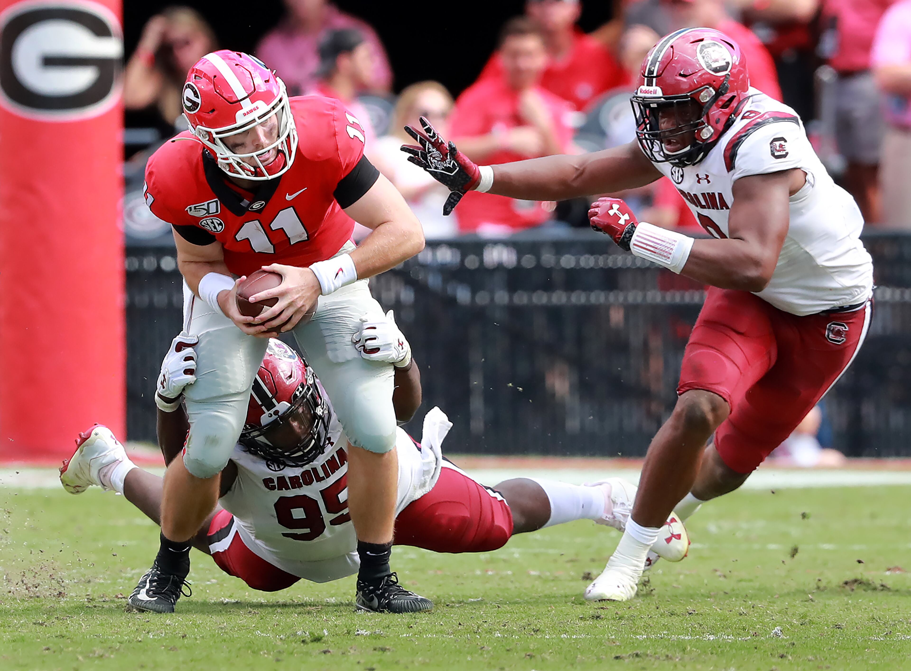 Georgia quarterback Jake Fromm is sacked by South Carolina defenders Kobe Smith (left) and D.J. Wonnum (right) during the third quarter in a NCAA college football game on Saturday, October, 12, 2019, in Athens. Curtis Compton/ccompton@ajc.com