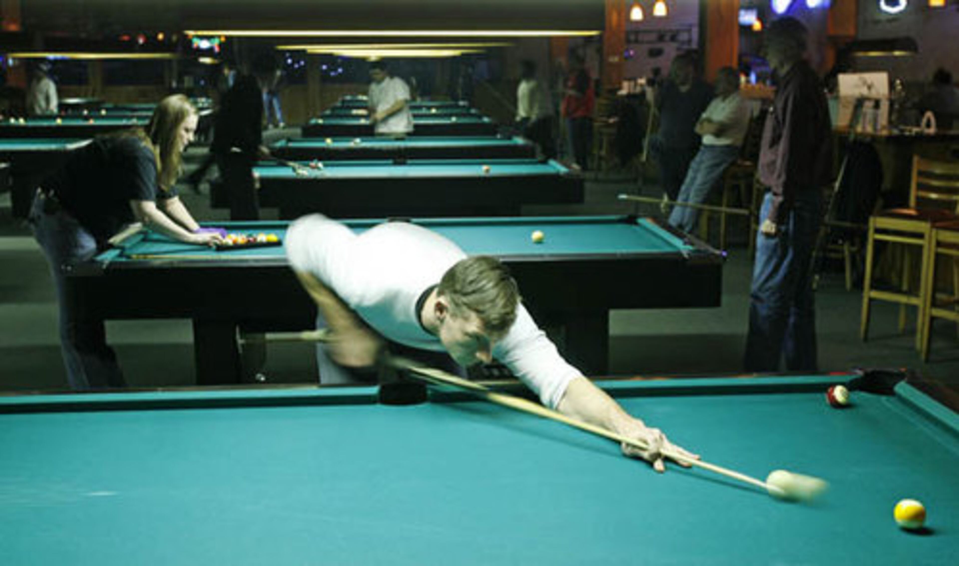 Chris Anderson, 33, of Marietta takes a shot at the 9-ball, while Stephanie Scheib, 24, (back) of Dallas racks up a game of 8-ball.