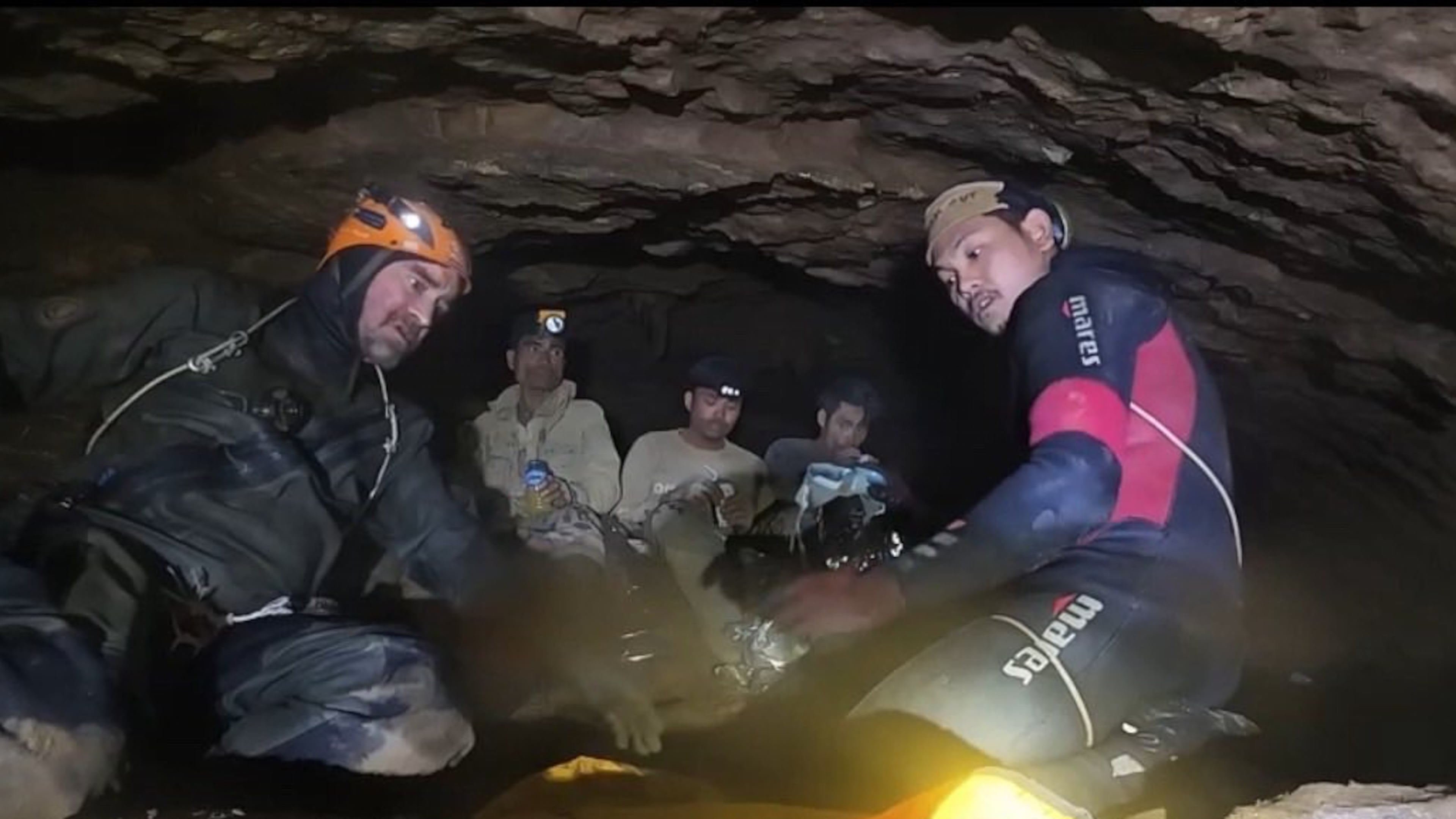 This image released by Benz Norrased Palasing Seascout Diving, two rescuers work before evacuating the first of five villagers who had been trapped in a cave, seen in the back, in Xaisomboun province, Laos, Friday, May 29, 2026. (Benz Norrased Palasing Seascout Diving via AP)