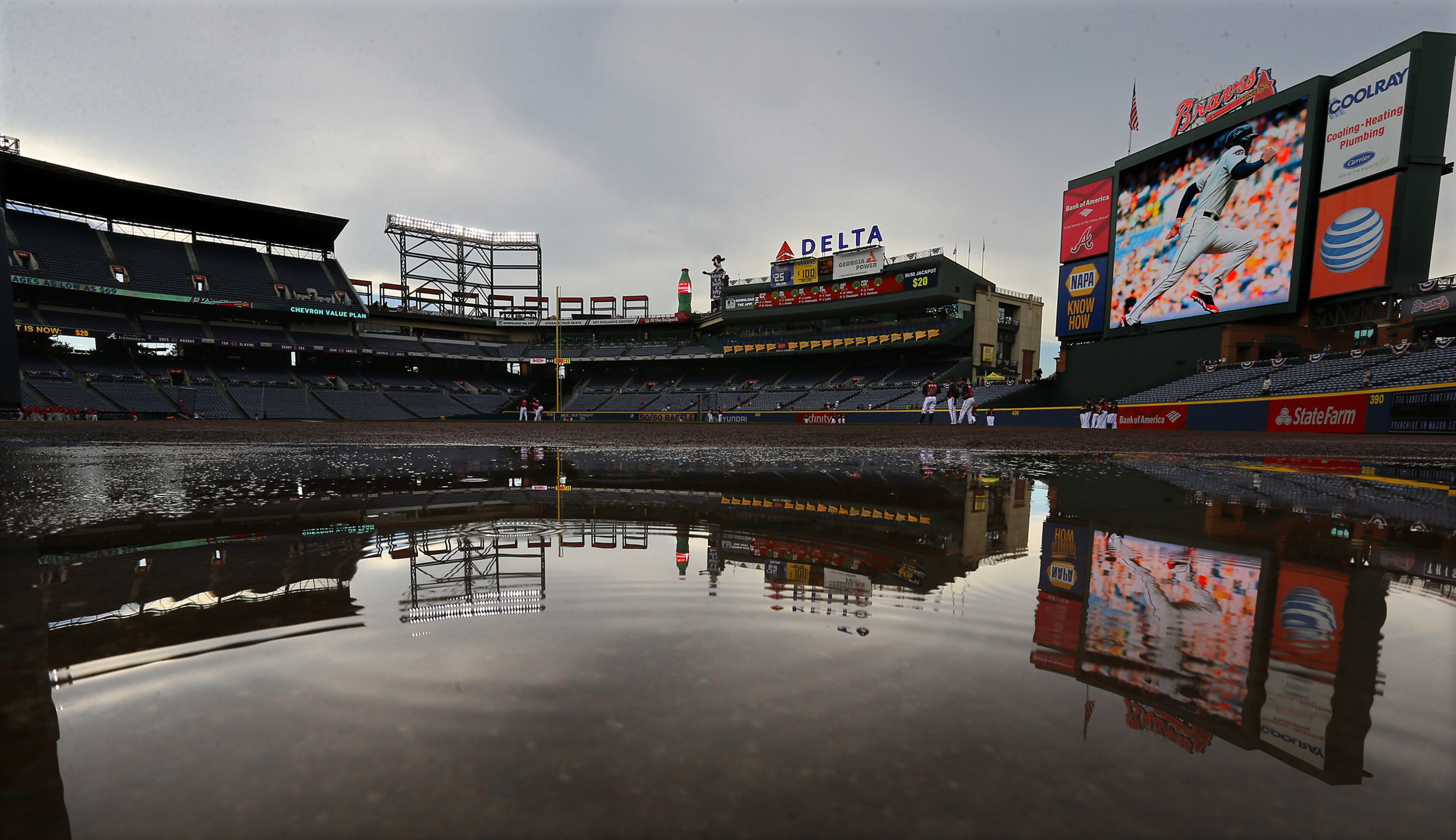 Turner Field Stadium is reflected in puddles of water from passing showers while the Braves and the Phillies take batting practice before playing in a baseball game on Tuesday, Sept. 2, 2014, in Atlanta. CURTIS COMPTON / CCOMPTON@AJC.COM