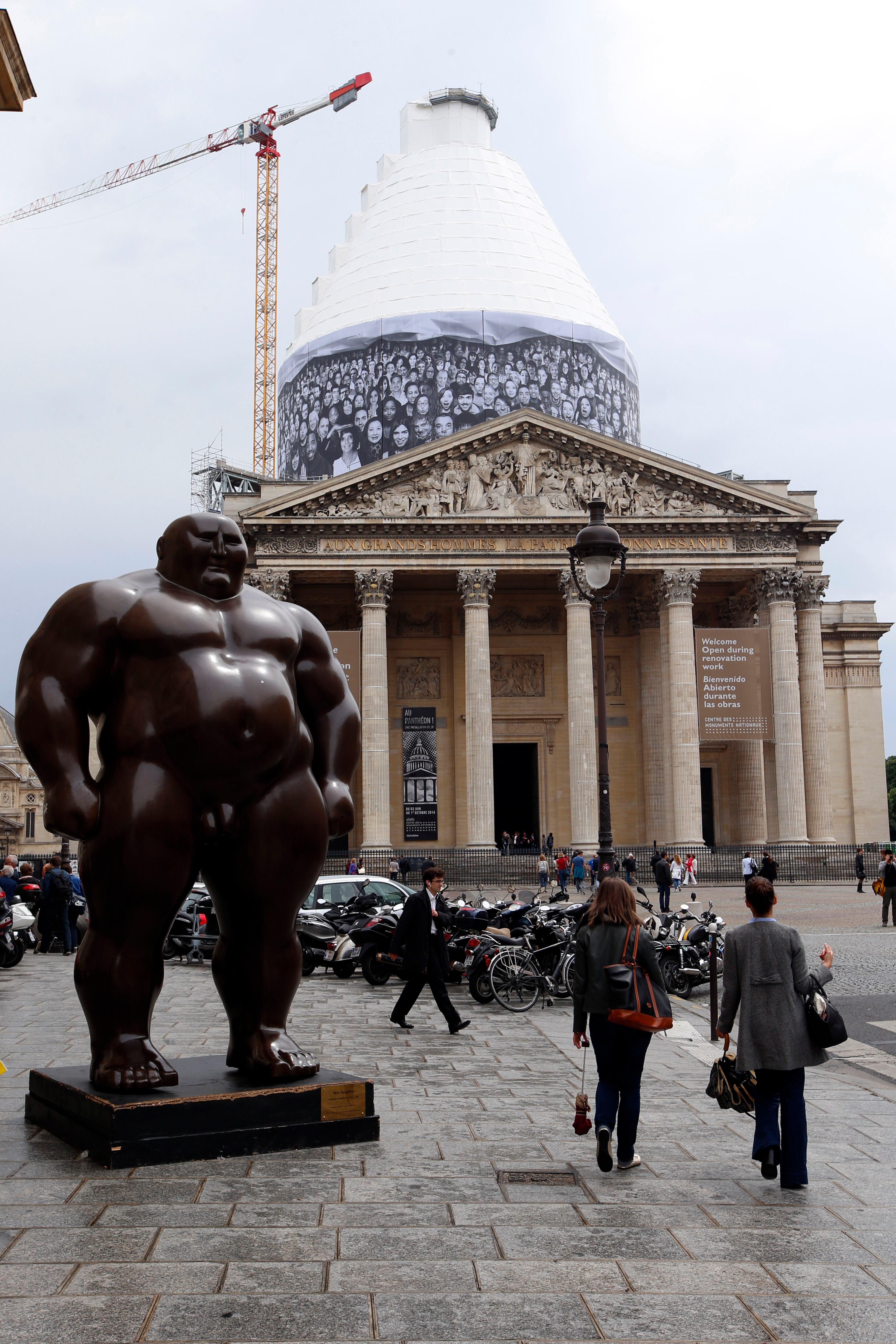A giant photos of portraits by French street artist and photographer JR decorates the dome of the Pantheon during the presentation of his creation in Paris, Tuesday, June 3, 2014. French Government named JR to decorate with portraits the dome of Paris' Pantheon, that is the final resting place for 72 of France's renowned men, and just one woman, as the monument is undergoing a 2 year renovation. At left is a "Mongolian (standing position) 2009" sculpture, by Chinese artist Shen Hong Biao.(AP Photo/Francois Mori)