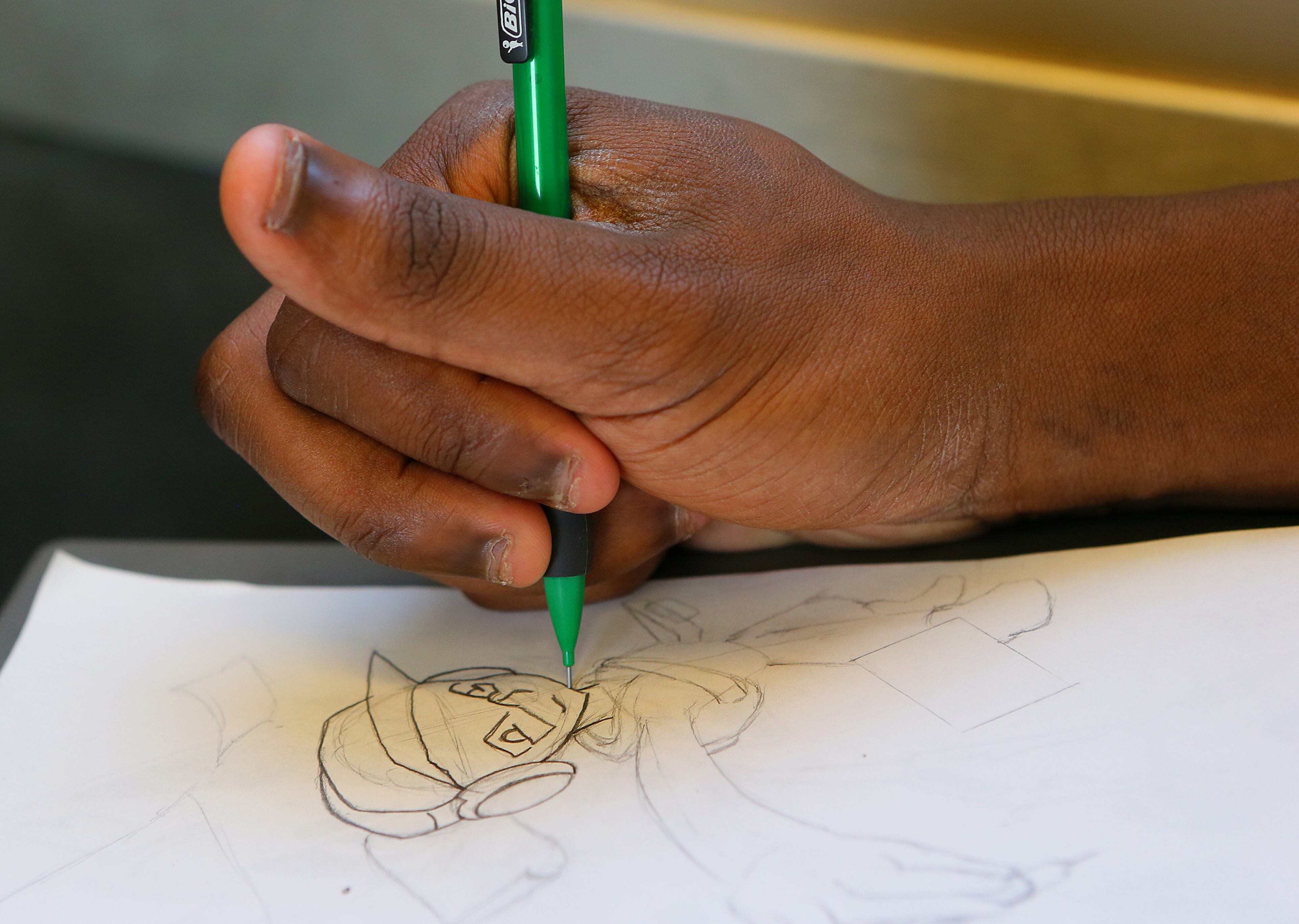 Omar sketches a self-portrait in pencil while riding a MARTA train to work. He hopes to work one day as a cartoonist.