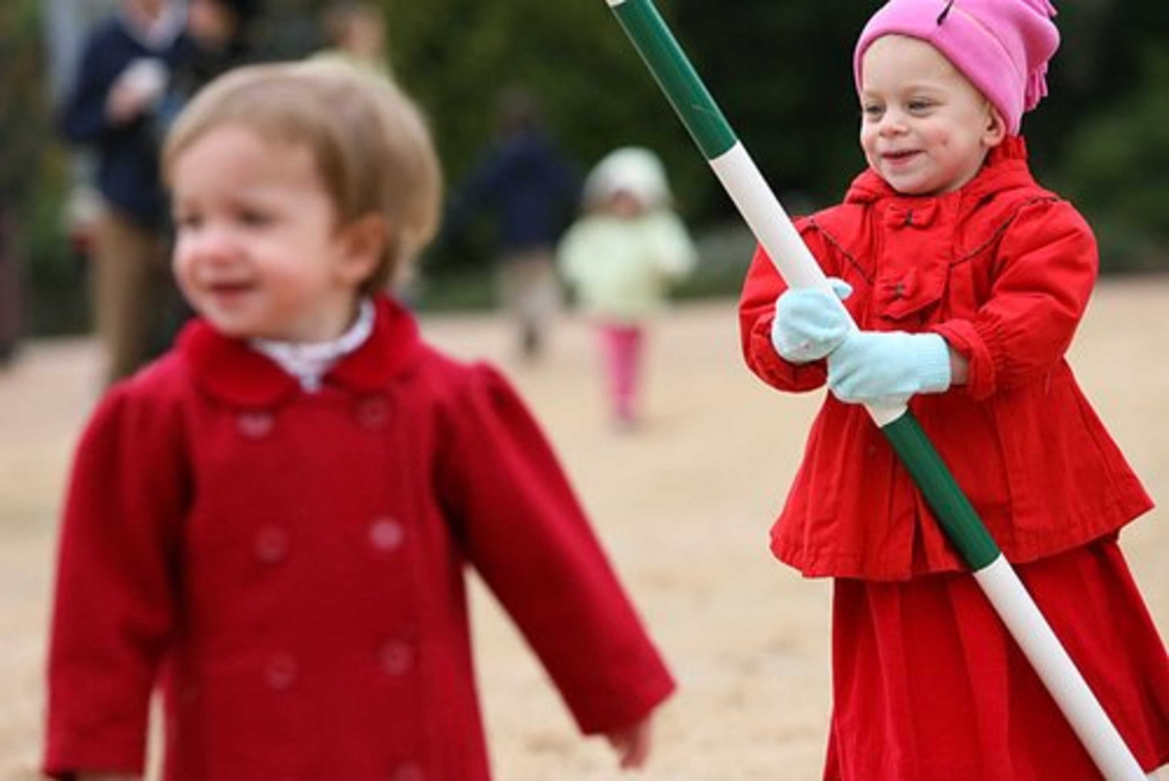 Alexis Dalton, 2, right, plays with a dog agility jumping pole while her friend Catherine Feeney checks out the dogs.