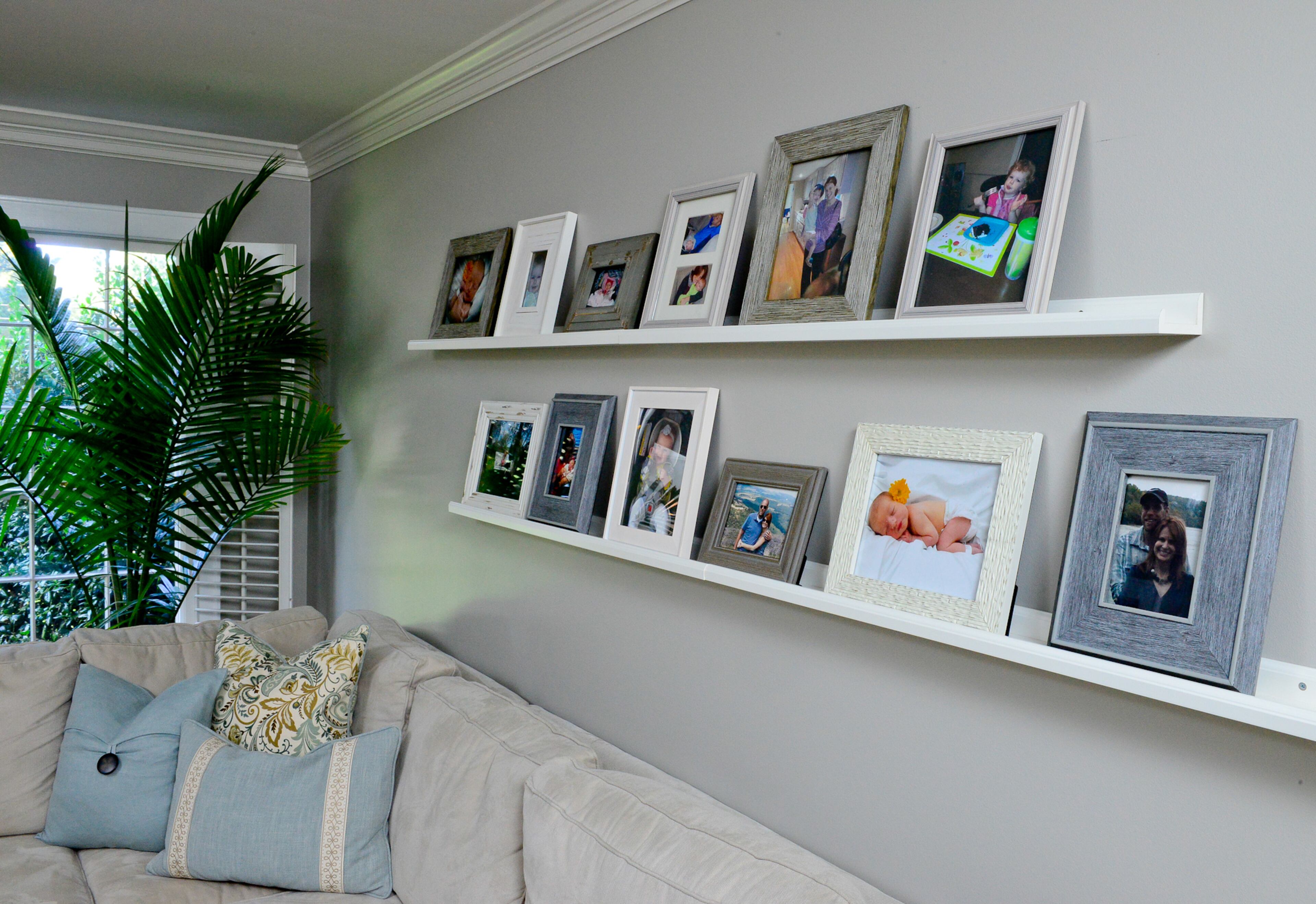 Ledges hold family memories, with a collection of photos in wood frames, on a wall painted Sherwin-Williams' Mindful Gray.