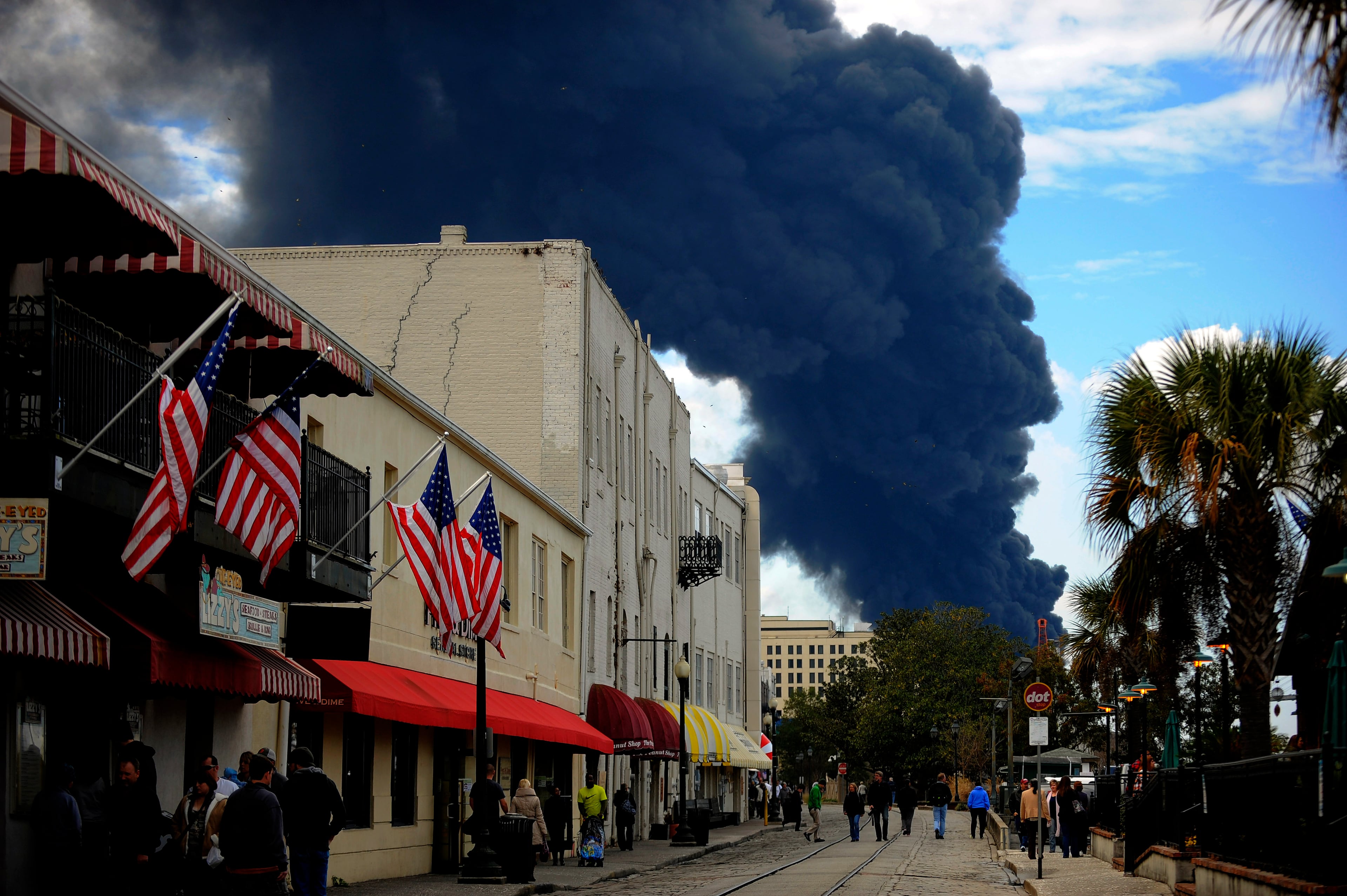 Visitor to Savannah's historic River Street watch a blaze in a warehouse at the Georgia Ports Authority Ocean Terminal, Saturday, Feb. 8, 2014, in Savannah, Ga. Burning rubber from the fire at the Port of Savannah sent up a towering column of black smoke that could be seen from miles away. The cause of the fire wasn't immediately known, but all port workers were accounted for and unharmed. (AP Photo/Stephen B. Morton)