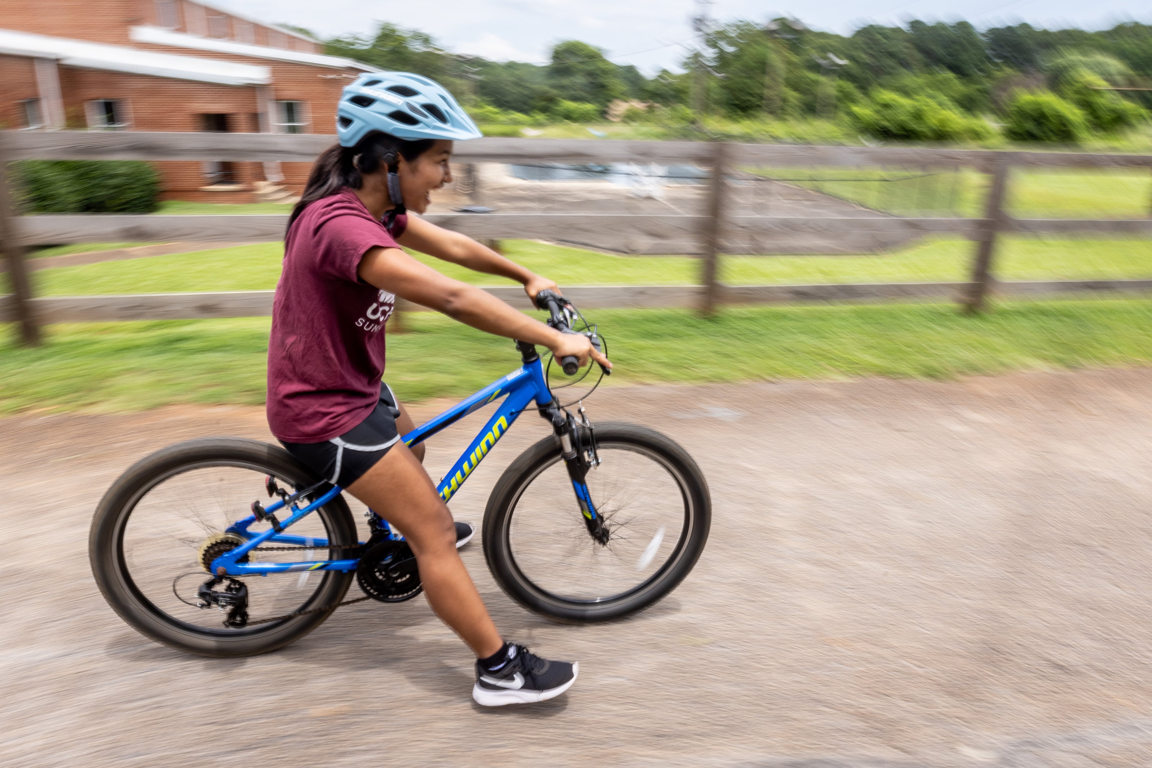 Mang Bor Cin glides down a shallow hill with her feet off the ground during Mang Bor Cin's first bike riding lesson in Decatur Saturday. July 23, 2023. (Steve Schaefer/steve.schaefer@ajc.com)