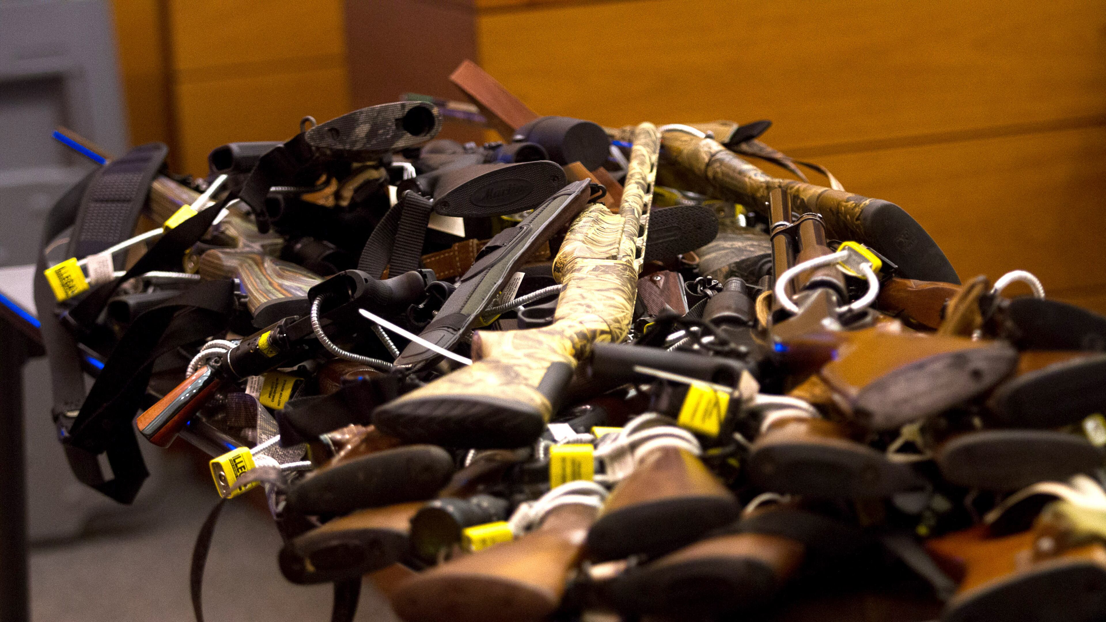 Tex McIver’s dozens of guns are piled onto table in court on Day 12 of McIver’s murder trial. Steve Schaefer / For the AJC