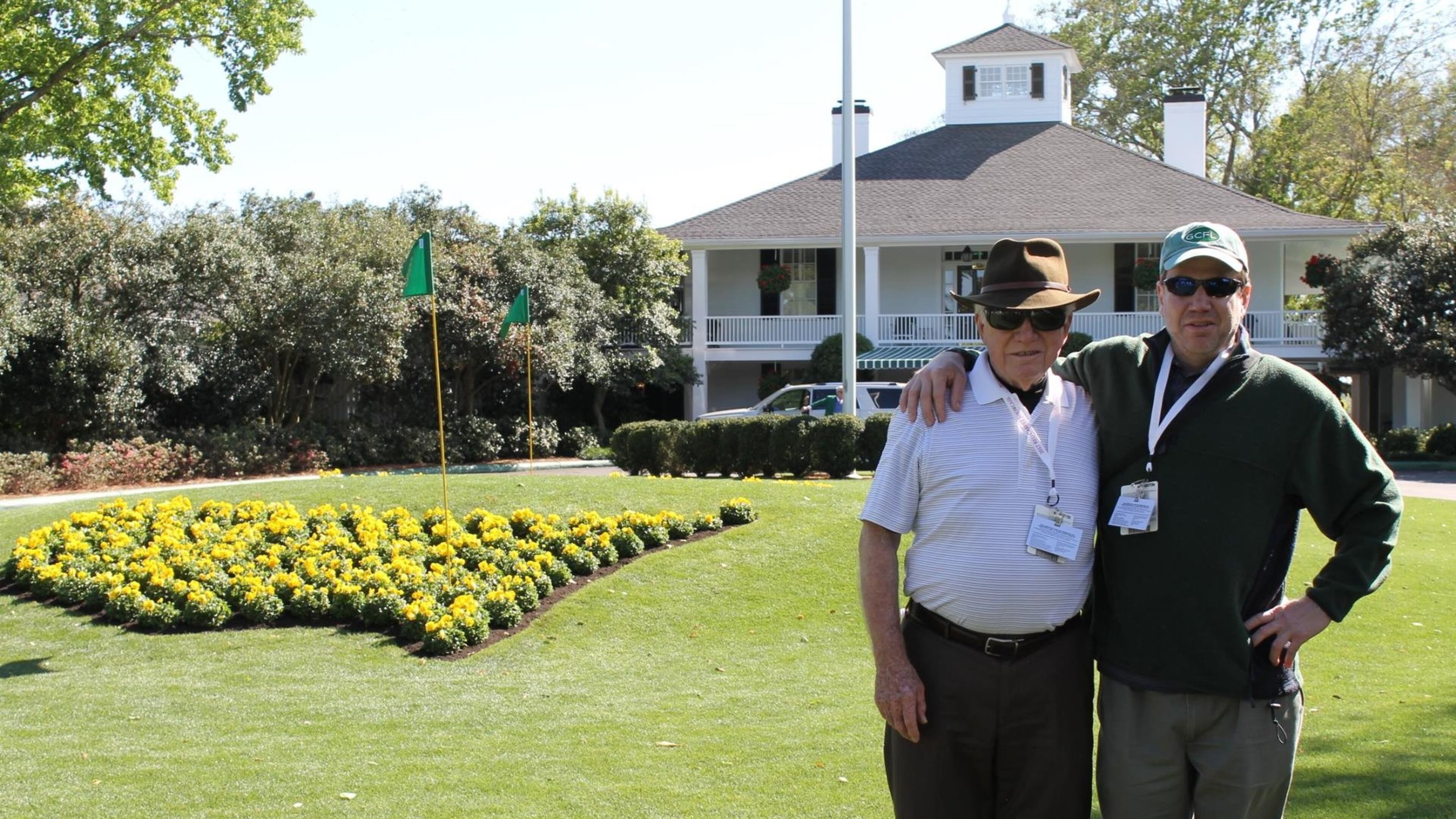 Cameras and cellphones are strictly forbidden at the Masters, but Augusta National does offer to take your picture in front of the clubhouse next to the iconic America-shaped flower bed. Pictured here, the author (right) with his father on their bucket-list trip to last year’s tournament. BLAKE GUTHRIE