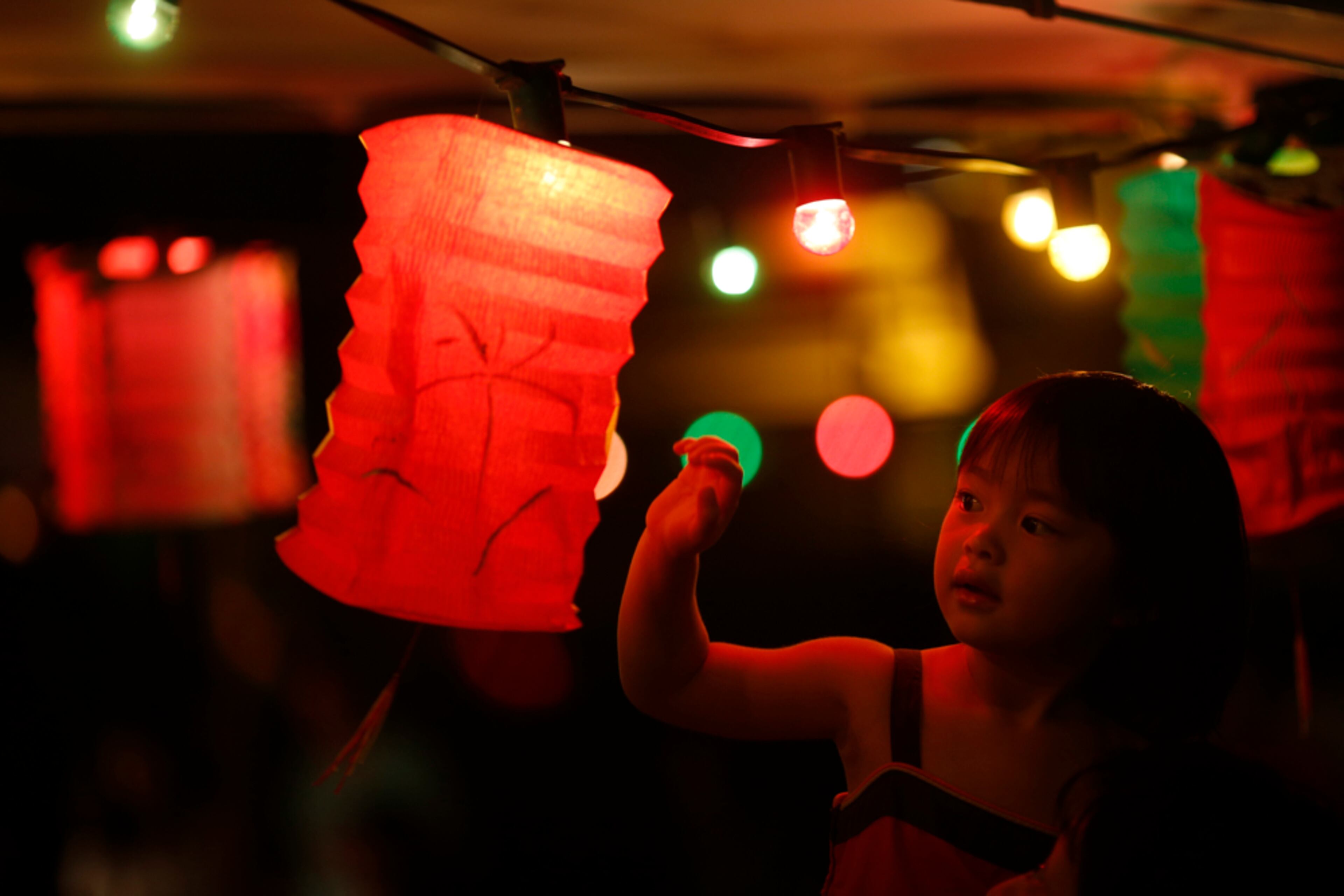 FESTIVAL LIGHT--A girl touches a lantern at an outdoor restaurant during the Chinese Mid-Autumn Festival in Hong Kong Sunday, Sept. 30, 2012. Like ancient Chinese poets, Hong Kong people appreciate the beauty of the full moon in the Mid-Autumn Festival.