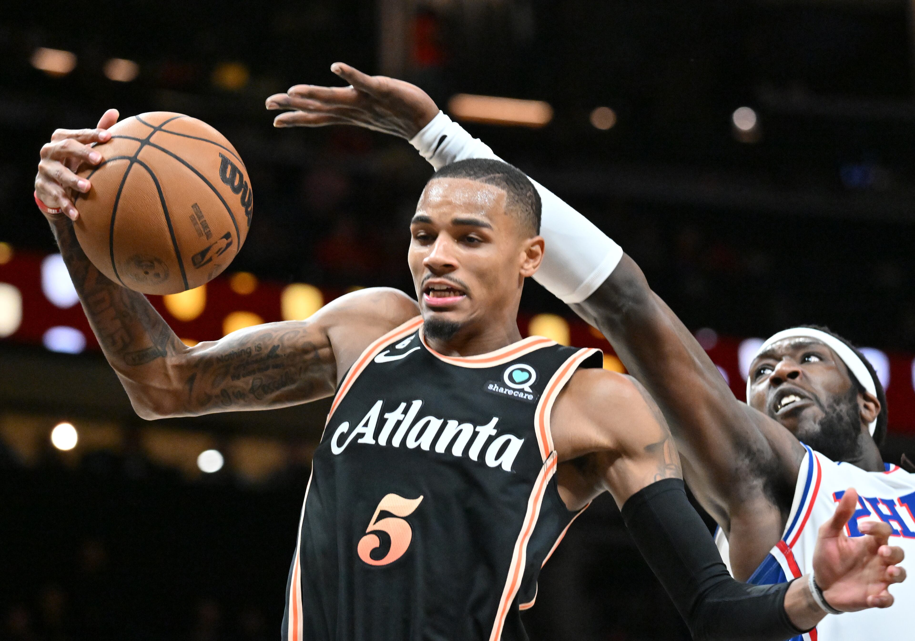 Hawks' guard Dejounte Murray (left) grabs a rebound against Philadelphia 76ers' center Montrezl Harrell (right). (Hyosub Shin / Hyosub.Shin@ajc.com)