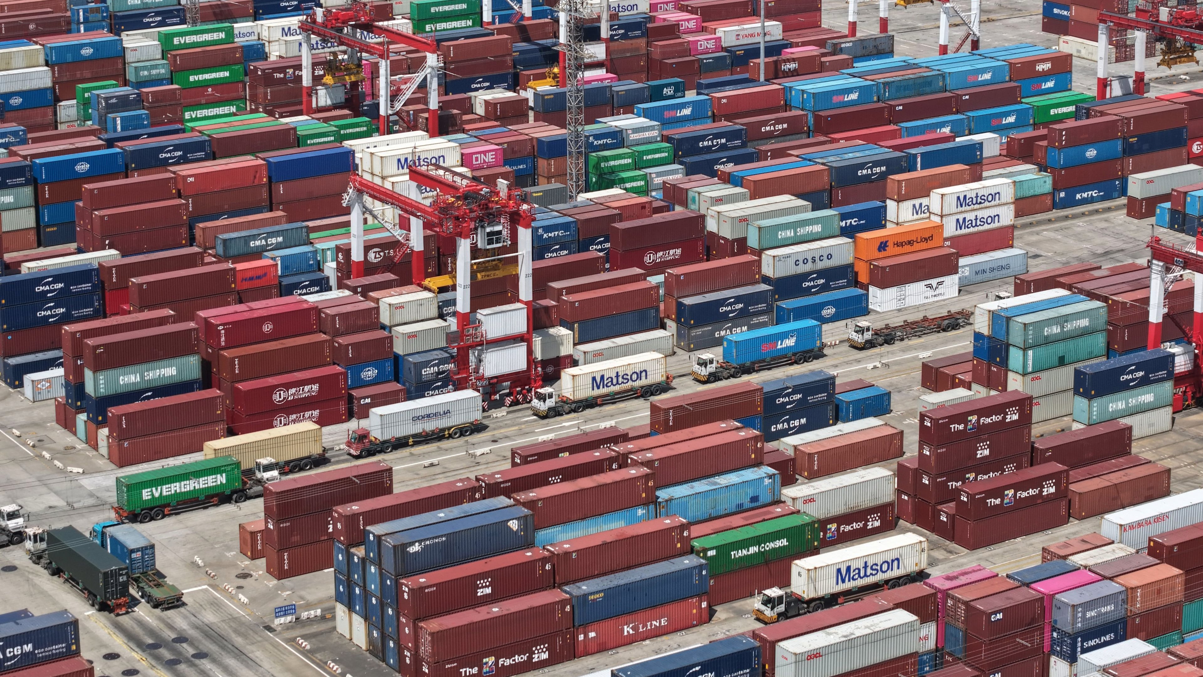 Trucks move past containers stored at a container terminal in Shanghai, China, Tuesday, July 14, 2026. (Chinatopix Via AP)