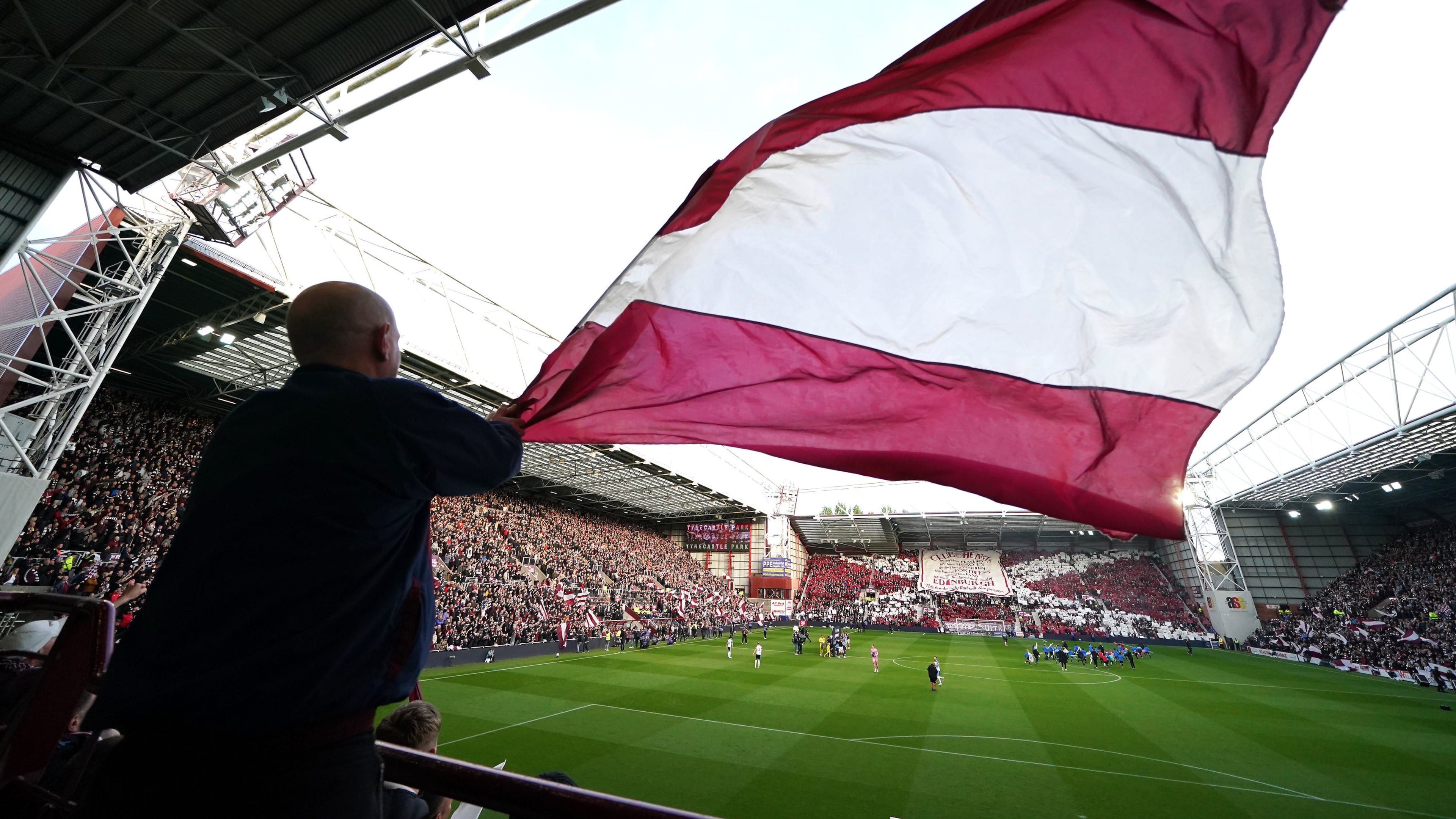 A Heart of Midlothian fan waves a large flag ahead the Scottish Premiership soccer match between Heart of Midlothian and Falkirk, Wednesday, May 13, 2026, in Edinburgh, Scotland. (Andrew Milligan/PA via AP)