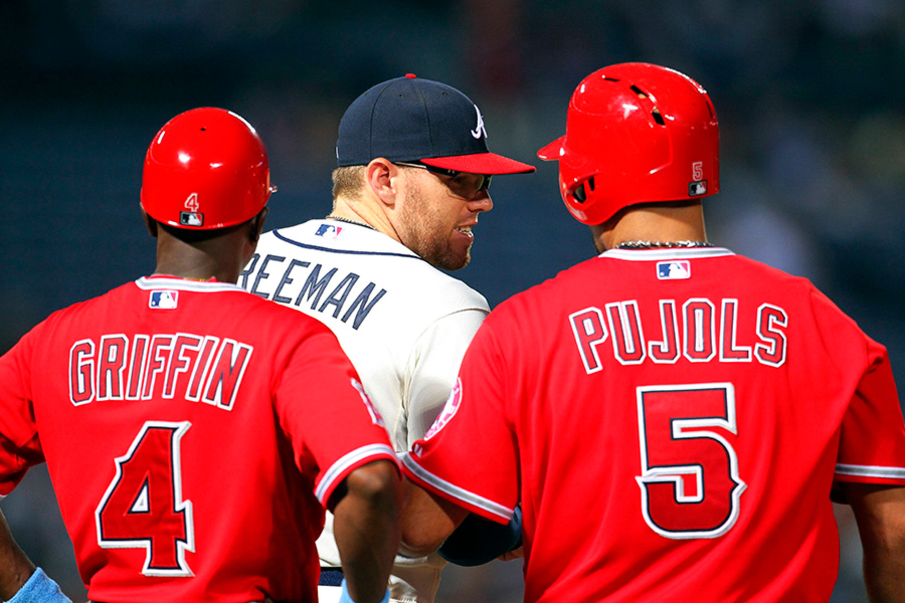 Los Angeles Angels' Albert Pujols (5) talks with Atlanta Braves first baseman Freddie Freeman (5) and first base coach Alfredo Griffin (4) after hitting a single in the third inning inning Sunday.