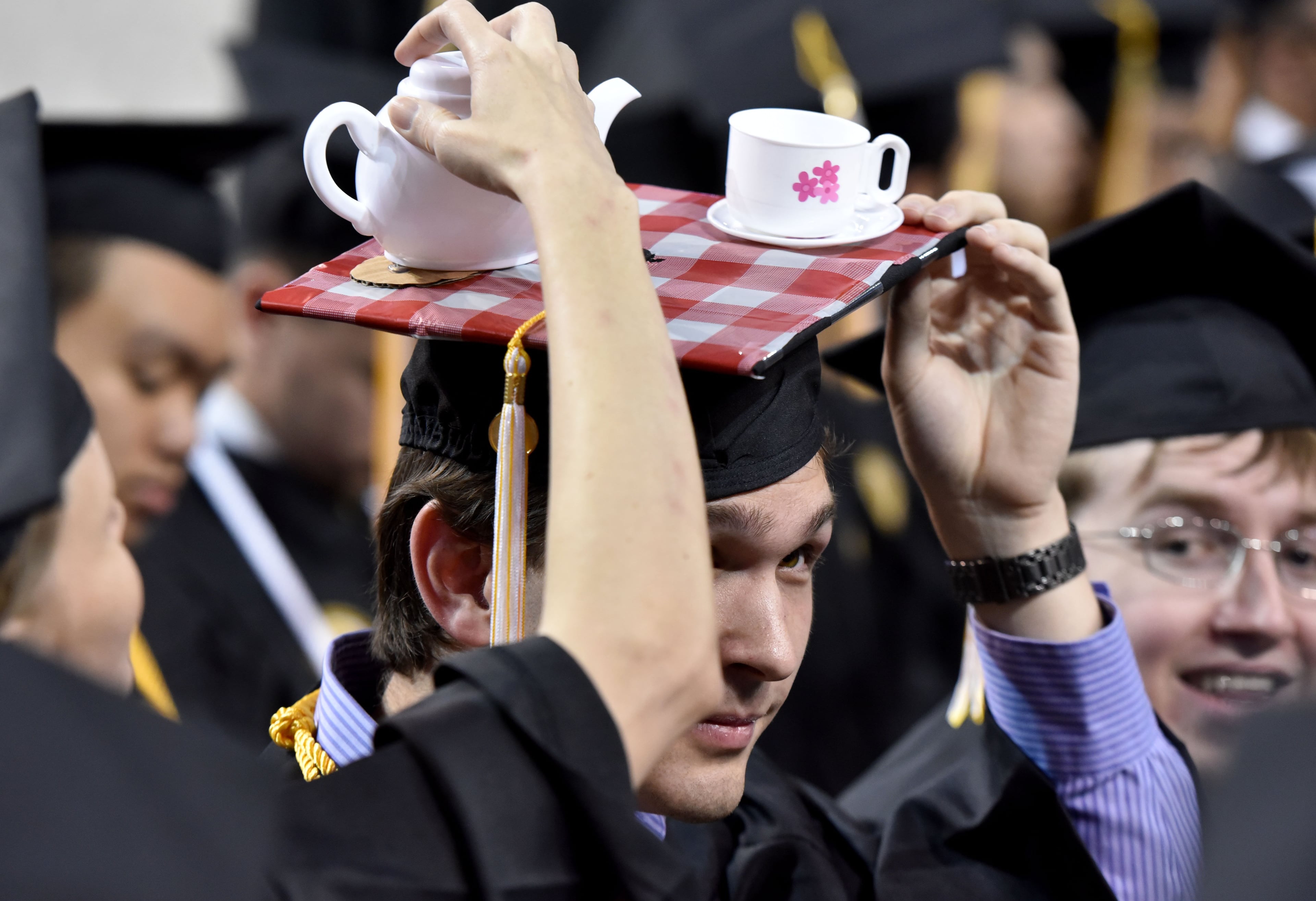Georgia Tech 2015: Andrew Schuster gets an assist with his mortarboard tea cups. (Hyosub Shin/AJC 2015 file)