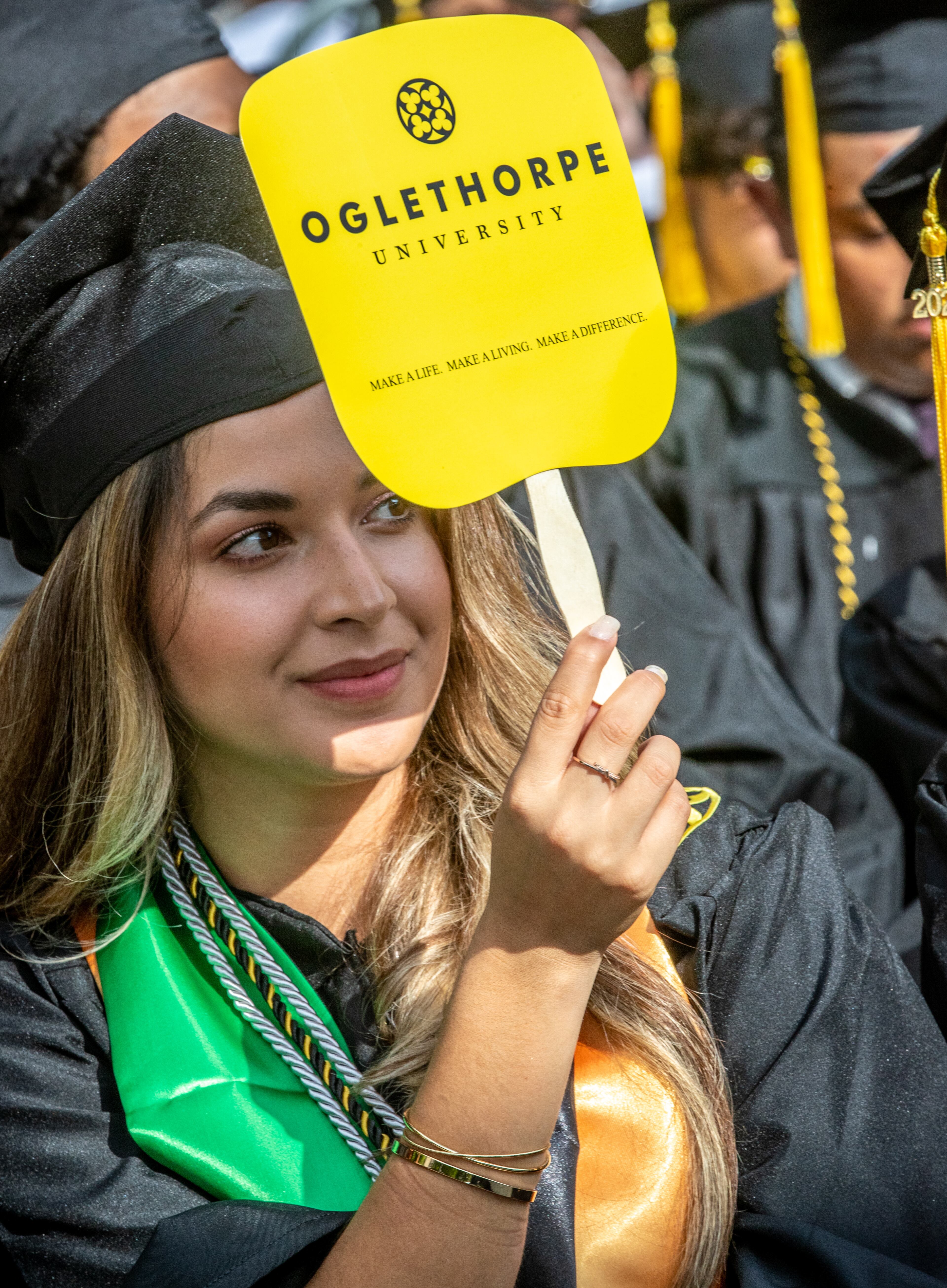 A graduate shades her eyes from the sun while listening to the speakers during Oglethorpe University's Class of 2022 commencement ceremony in the academic quadrangle Saturday, May 21, 2022. (Steve Schaefer /