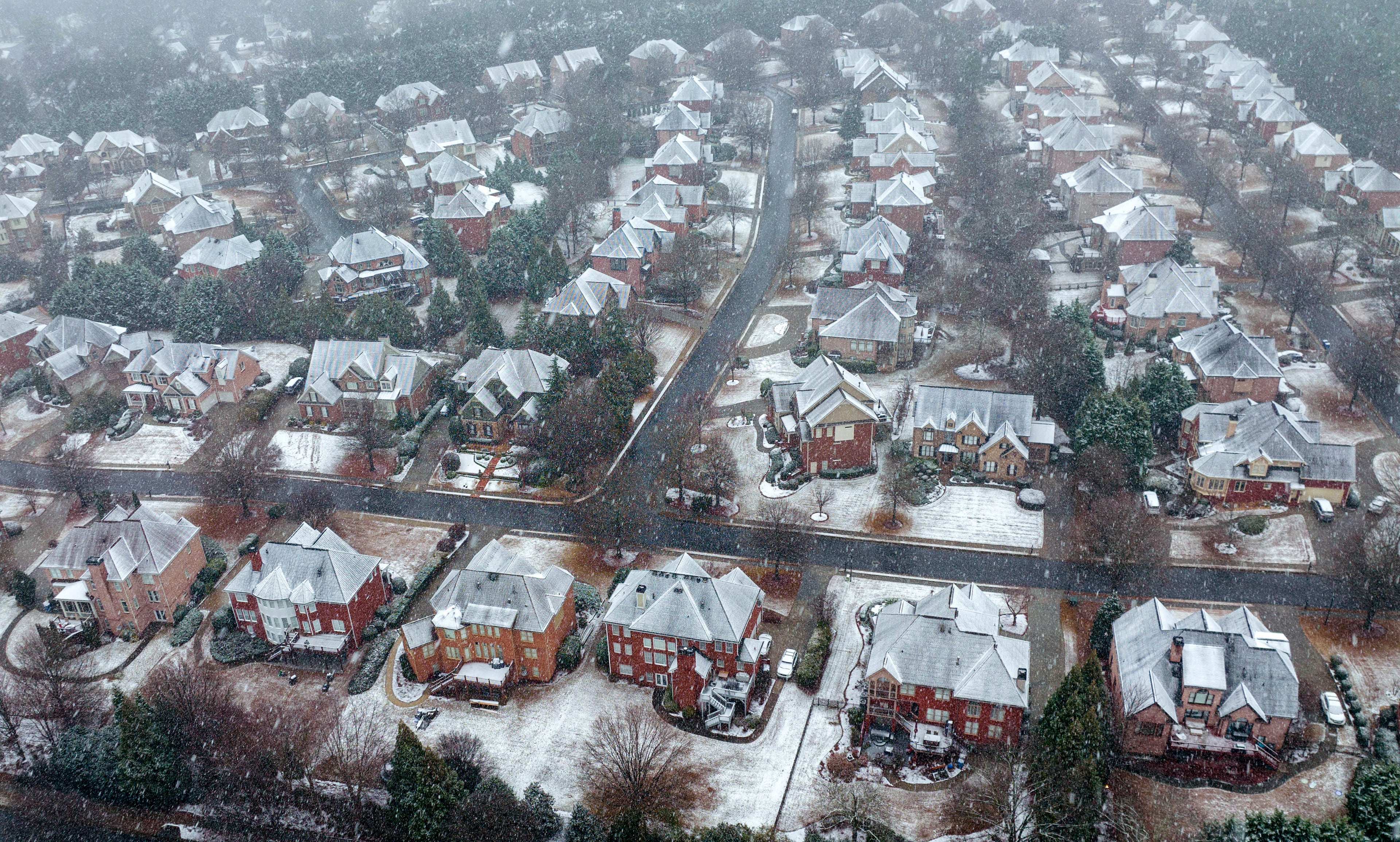 January 16, 2022 Snellville - Snow falls on houses in Snellville on Sunday, January 16, 2022. Snowfall continues to move south of I-285 and south Fulton and Coweta counties could see up to 2 inches of snow by Sunday evening. Major impacts near Lake Lanier and into the North Georgia mountains are being felt and certain spots could see up to 10 inches of snow. As of around noon, snow is moving through Troup and Coweta counties, as Fayette and Clayton counties still patiently wait for some flurries amidst the rain and some wintry mix. (Hyosub Shin / Hyosub.Shin@ajc.com)