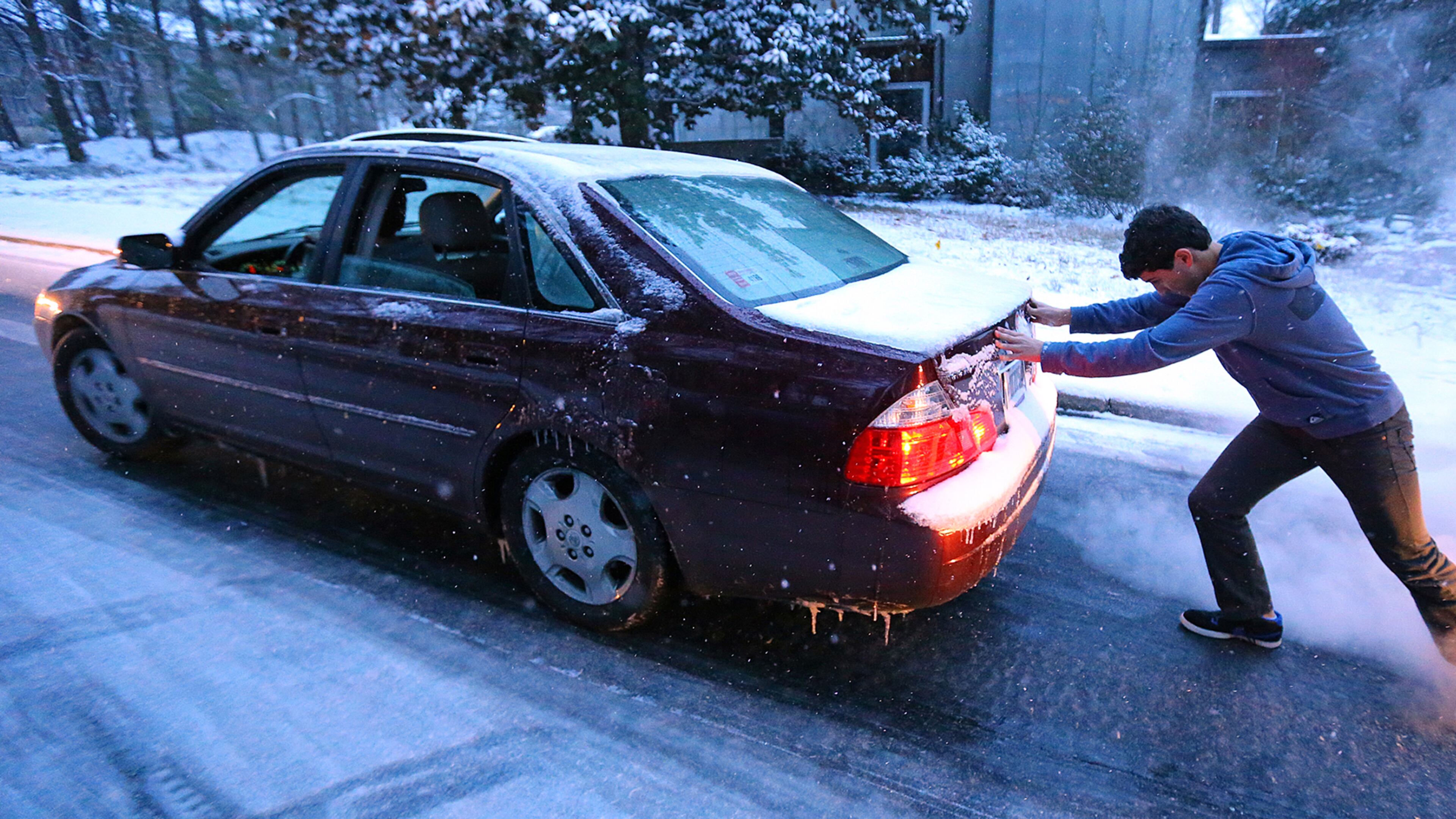Sammy Rouchdi pushes a stranded motorist, Cameron Scheeler, up an iced-over hill on Womack Road in Dunwoody after he became stuck on the ice trying to get home on Tuesday.