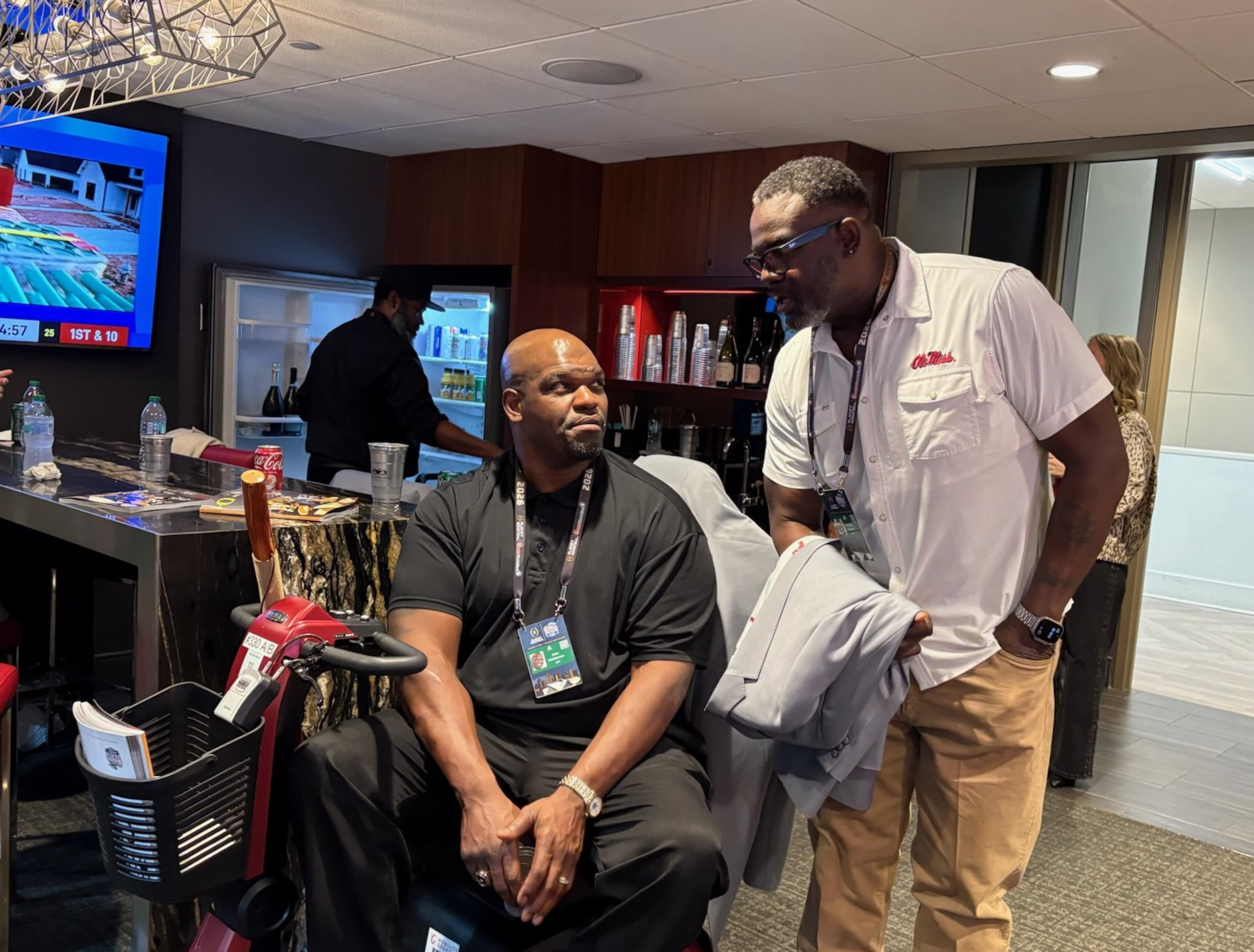 College Football Hall of Fame inductees John Henderson (left) and Terrence Metcalf share a conversation in a suite during the Peach Bowl at Mercedes-Benz Stadium on Friday, Jan. 9, 2026, in Atlanta. The game is another chance for the greats to hang out, swap stories and fanboy each other. (Ken Sugiura/AJC)