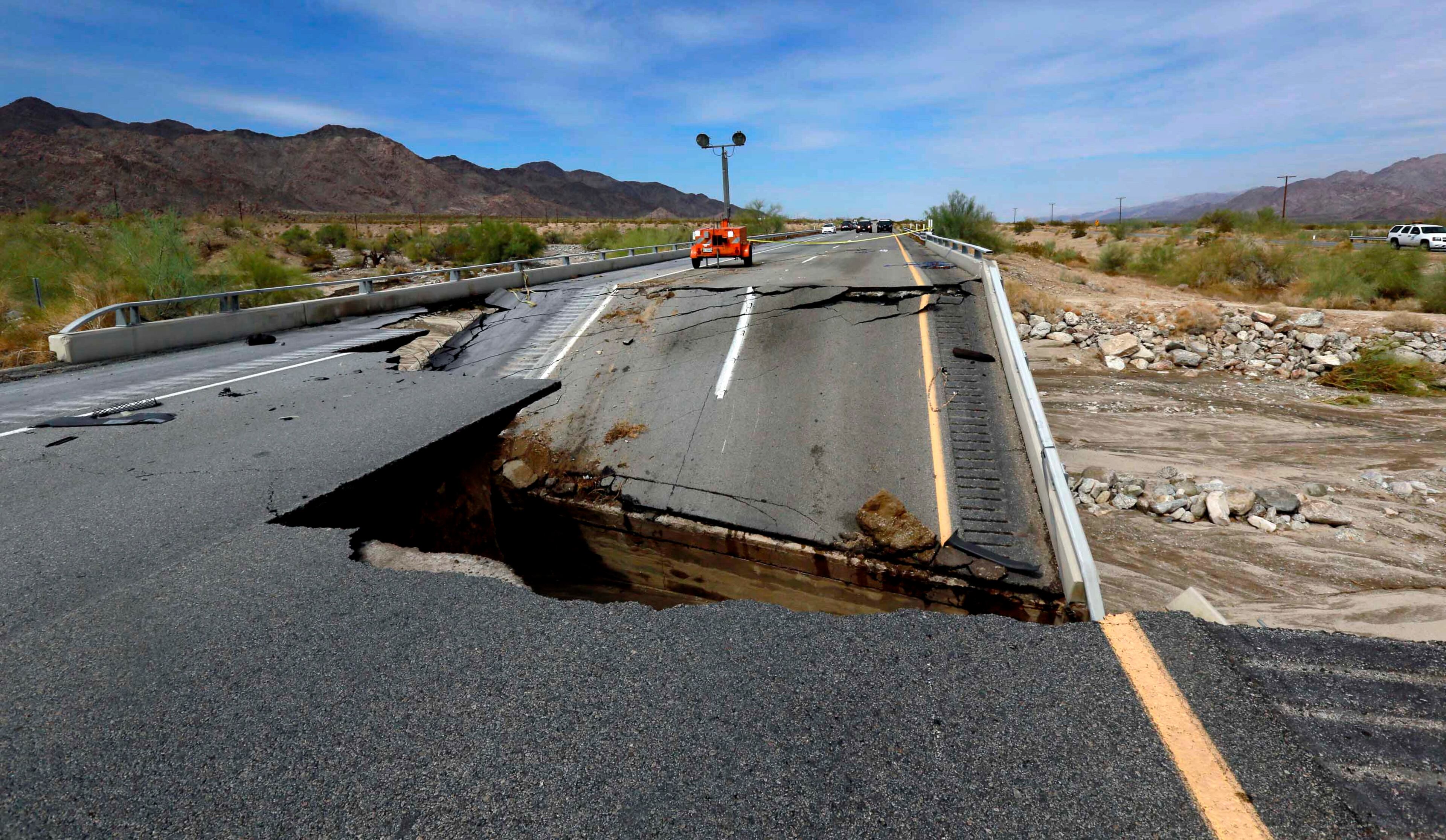 Damage is seen from a washed-out bridge near the town of Desert Center along Interstate 10 in Southern California, Monday, July 20, 2015. All traffic along one of the major highways connecting California and Arizona was blocked indefinitely when the bridge over a desert wash collapsed during a major storm, and the roadway in the opposite direction sustained severe damage. (AP Photo/Nick Ut)