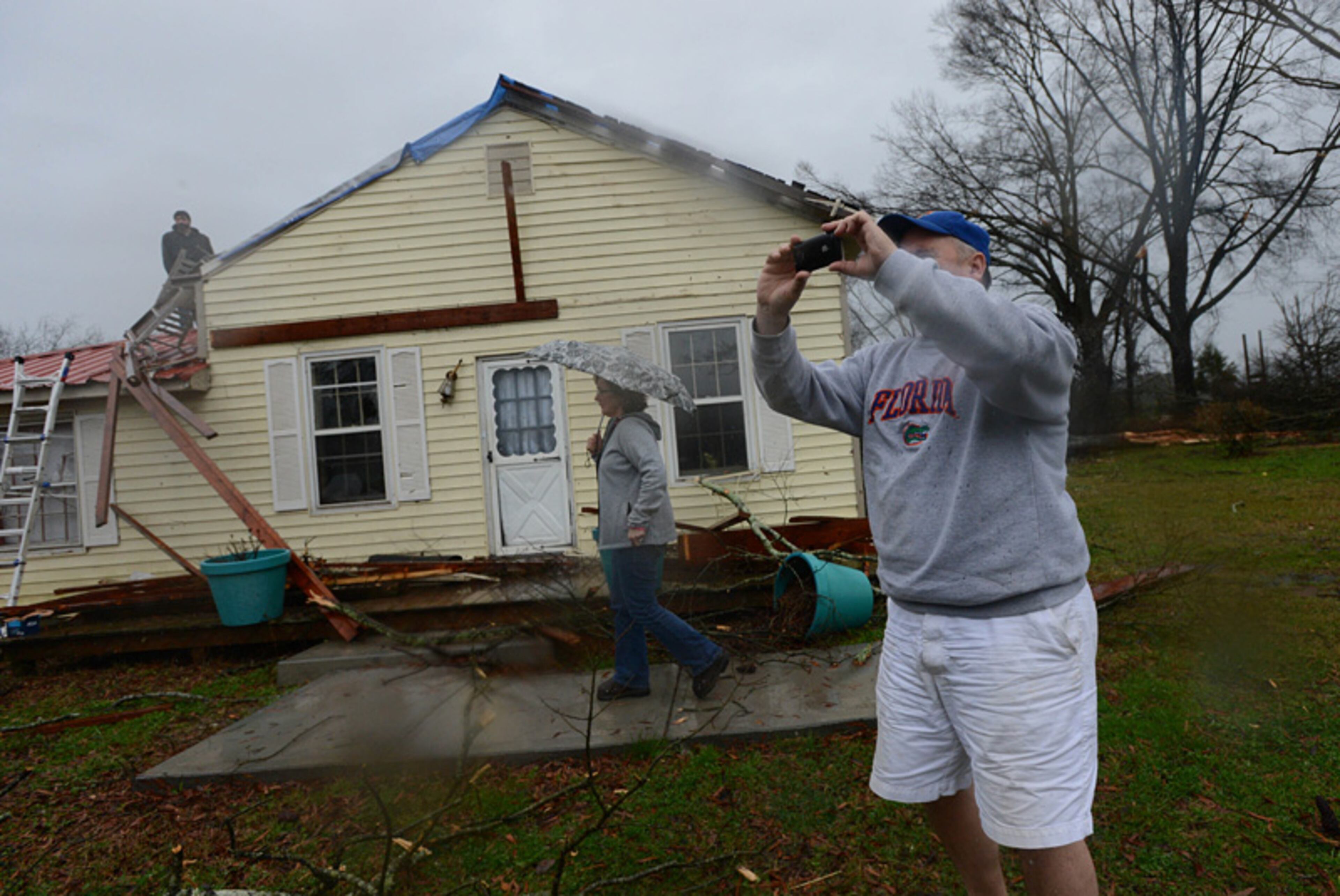 Wayne Moore takes a picture as his wife Sherry Moore tries to get in their damaged home Wednesday afternoon in Adairsville.