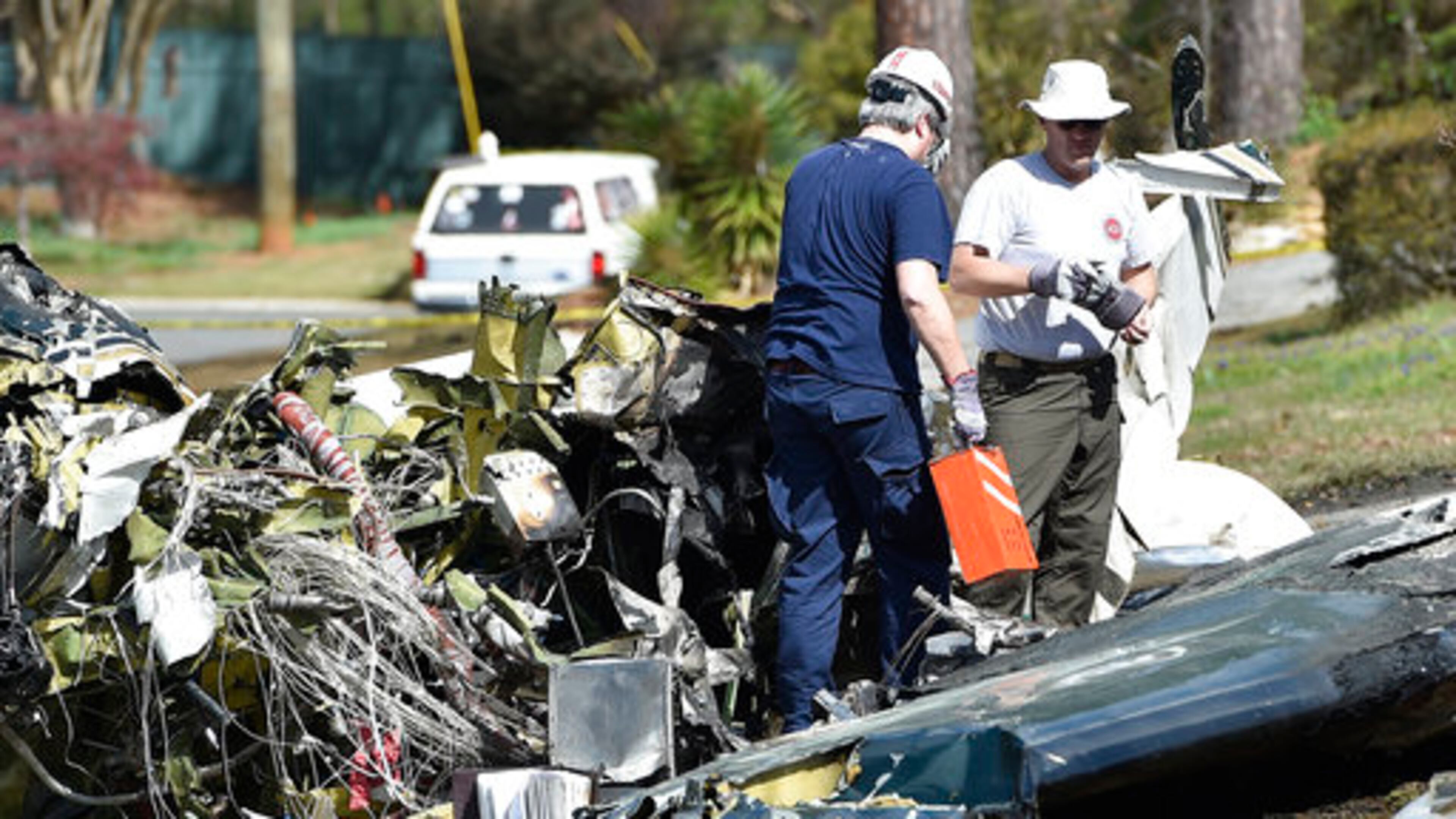 Officials with the National Transportation Safety Board and FAA remove a black box from the crashed Cessna Citation I on Saturday in Cobb County. (Credit: The Associated Press)
